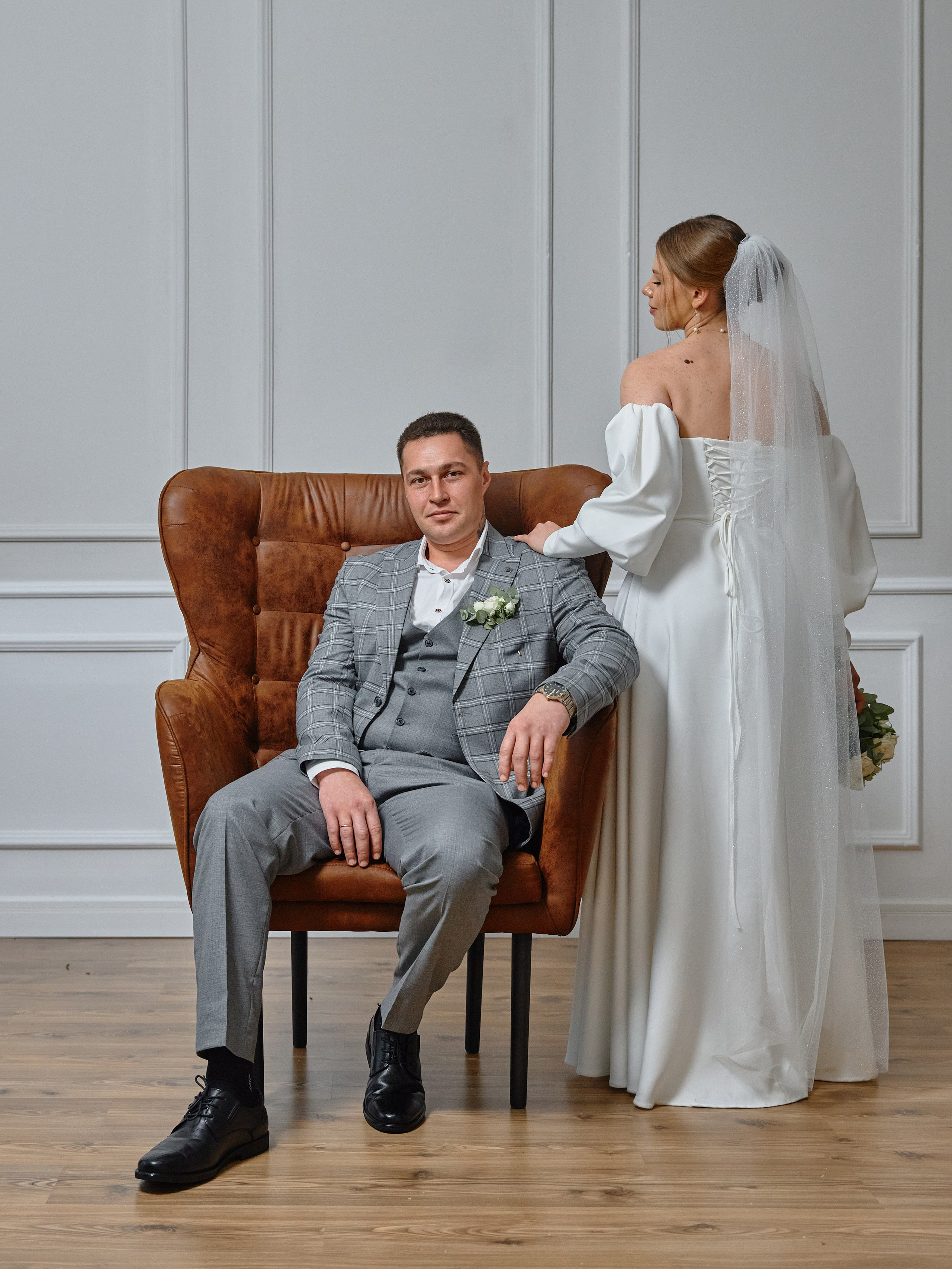 Жених в кресле рядом с невестой в фотостудии Анапы