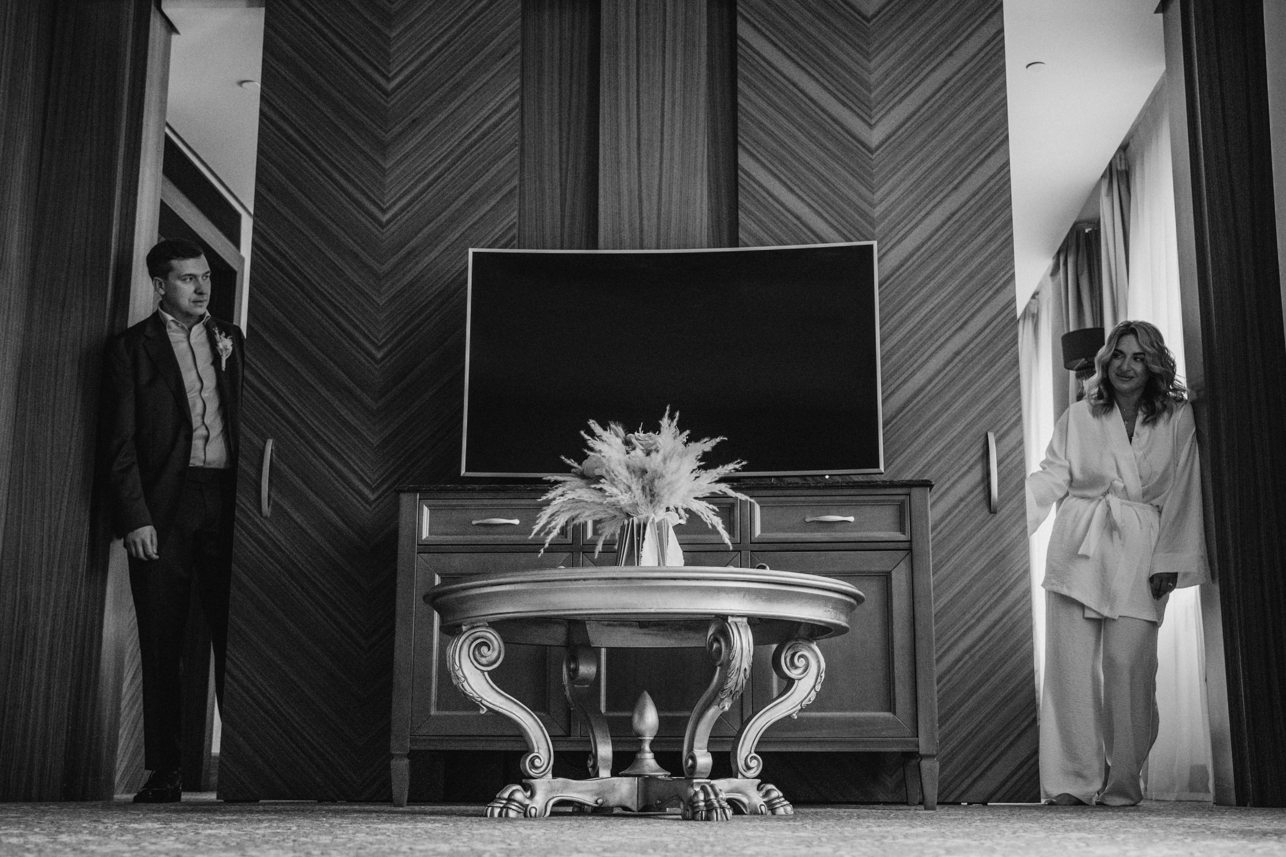 Жених смотрит в окно, задумчиво ожидая начала церемонии — атмосферные и искренние свадебные фотографии.