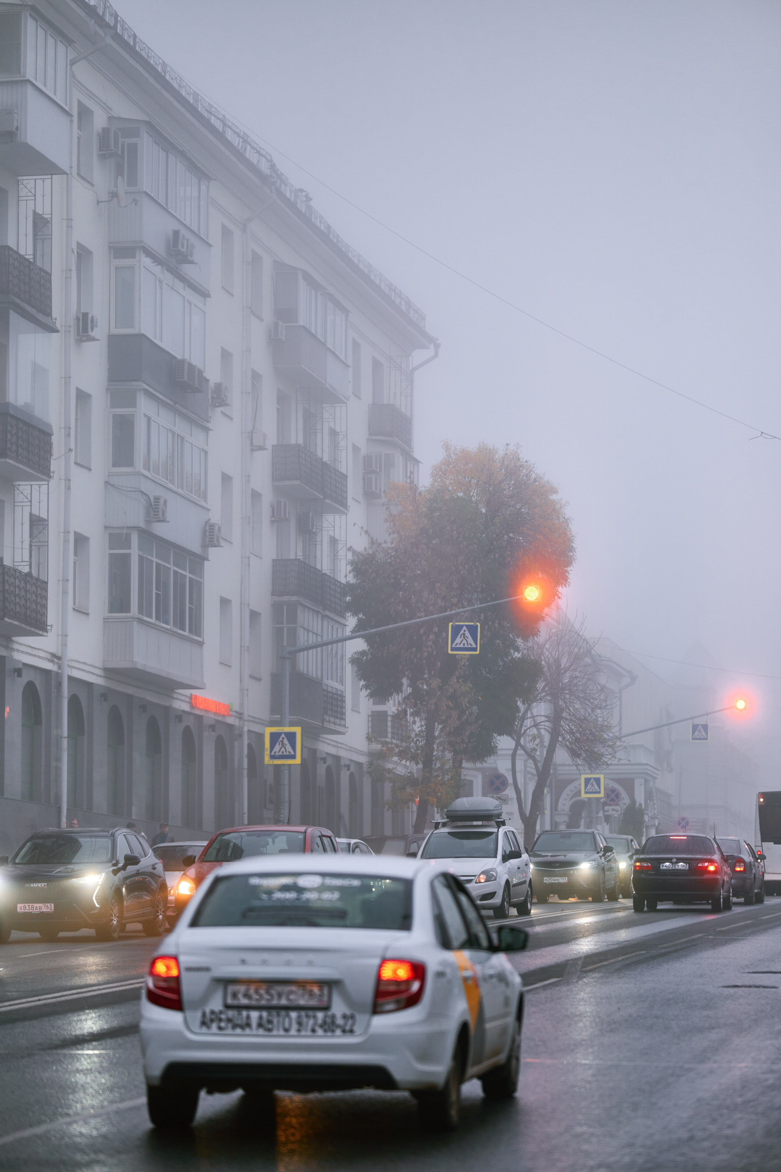 Автомобиль движется по дороге, скрытой густым туманом, который придаёт сцене сюрреалистичность