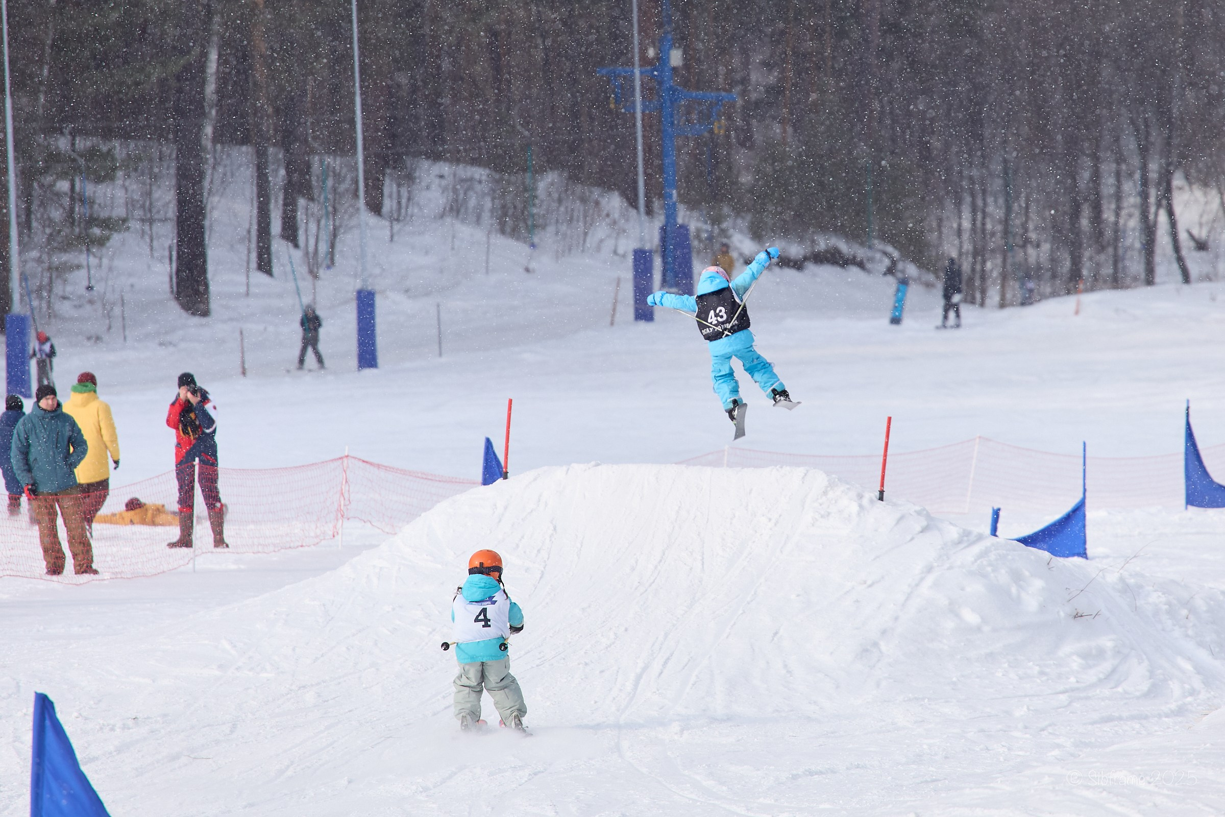 Две маленькие лыжницы заезжают на трамплин