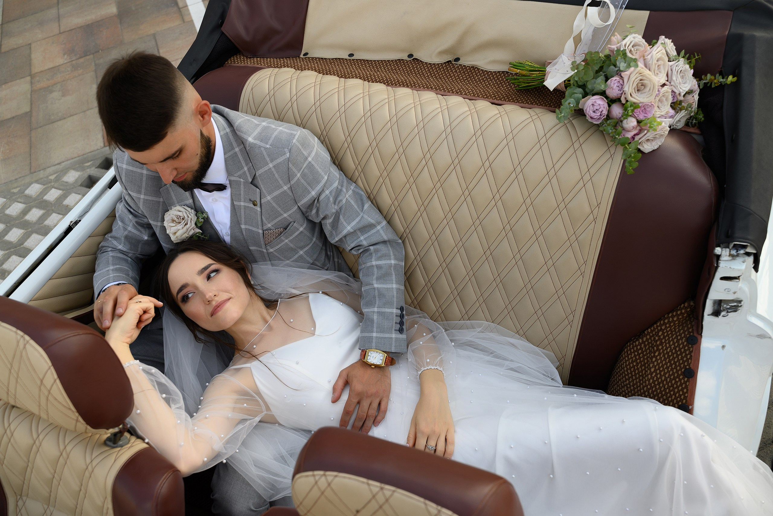 Фотография молодоженов, лежащих на зеднем сидении, в ретро-автомобиле, сделанная лучшим свадебным фотографом Краснодара.