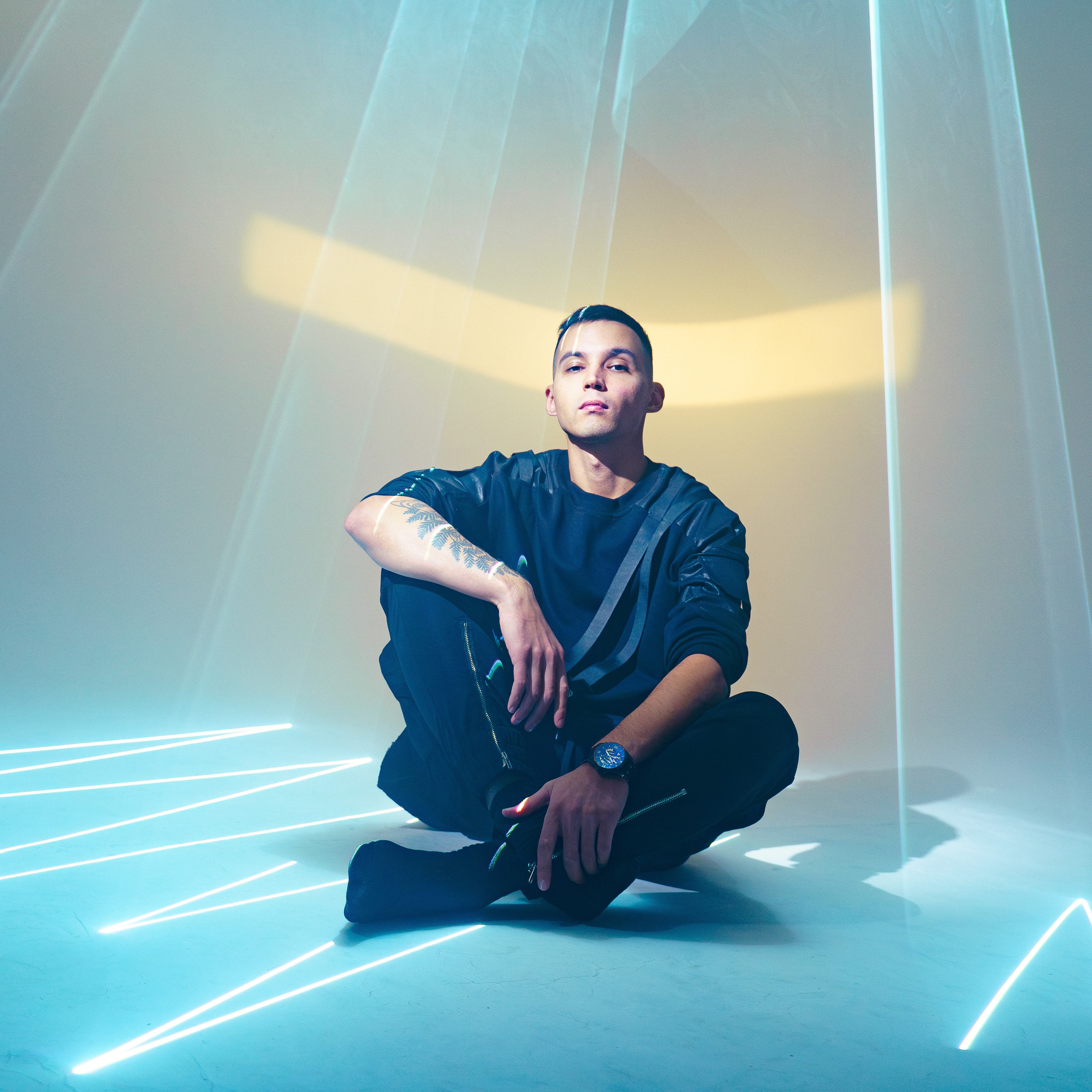 Мужчина сидит на полу среди расходящихся лазерных линий