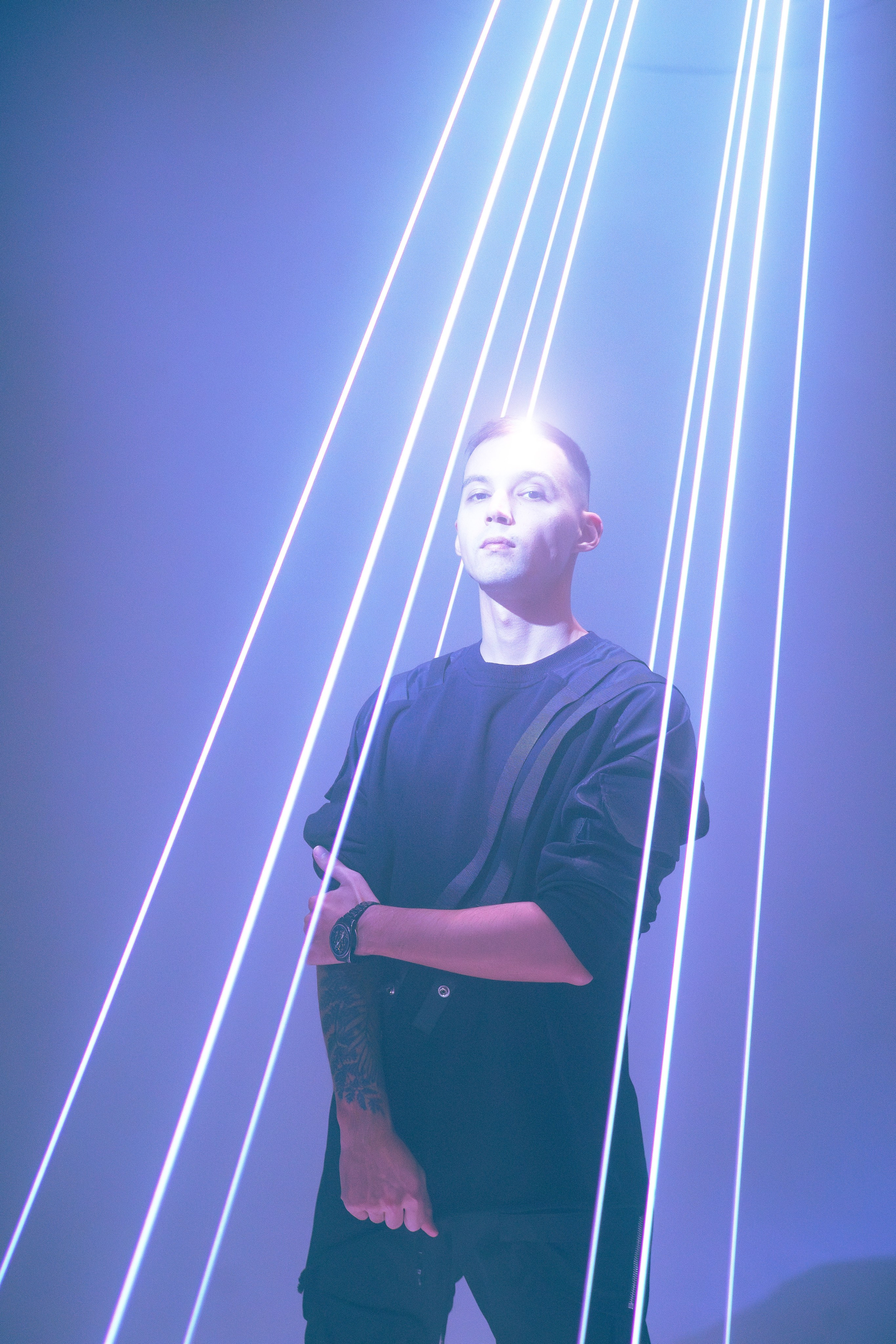 Мужчина позирует перед вертикальными лазерными лучами