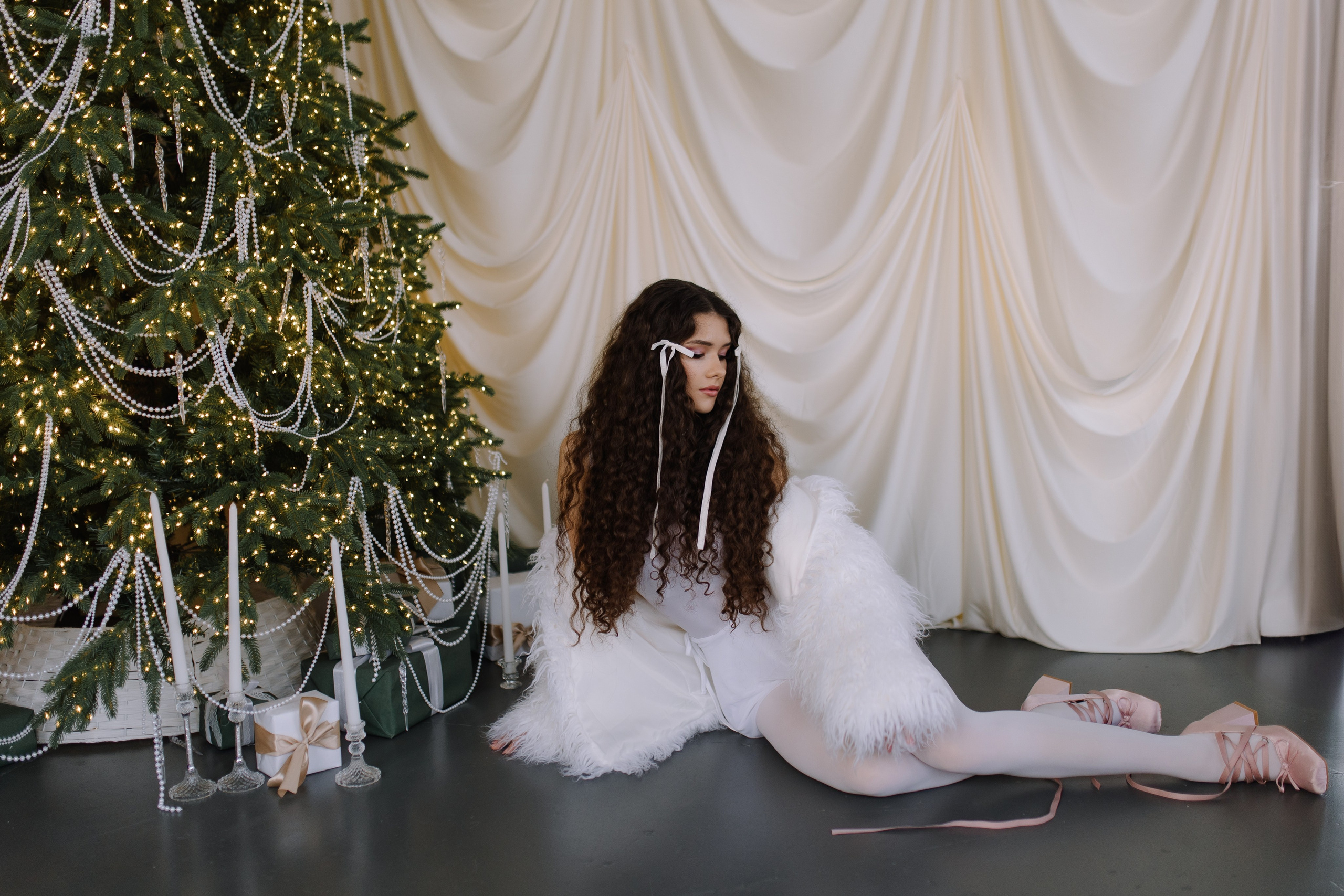 Фото девушки в гламурной зимней одежде, окруженной разноцветными шарами и звездочками.