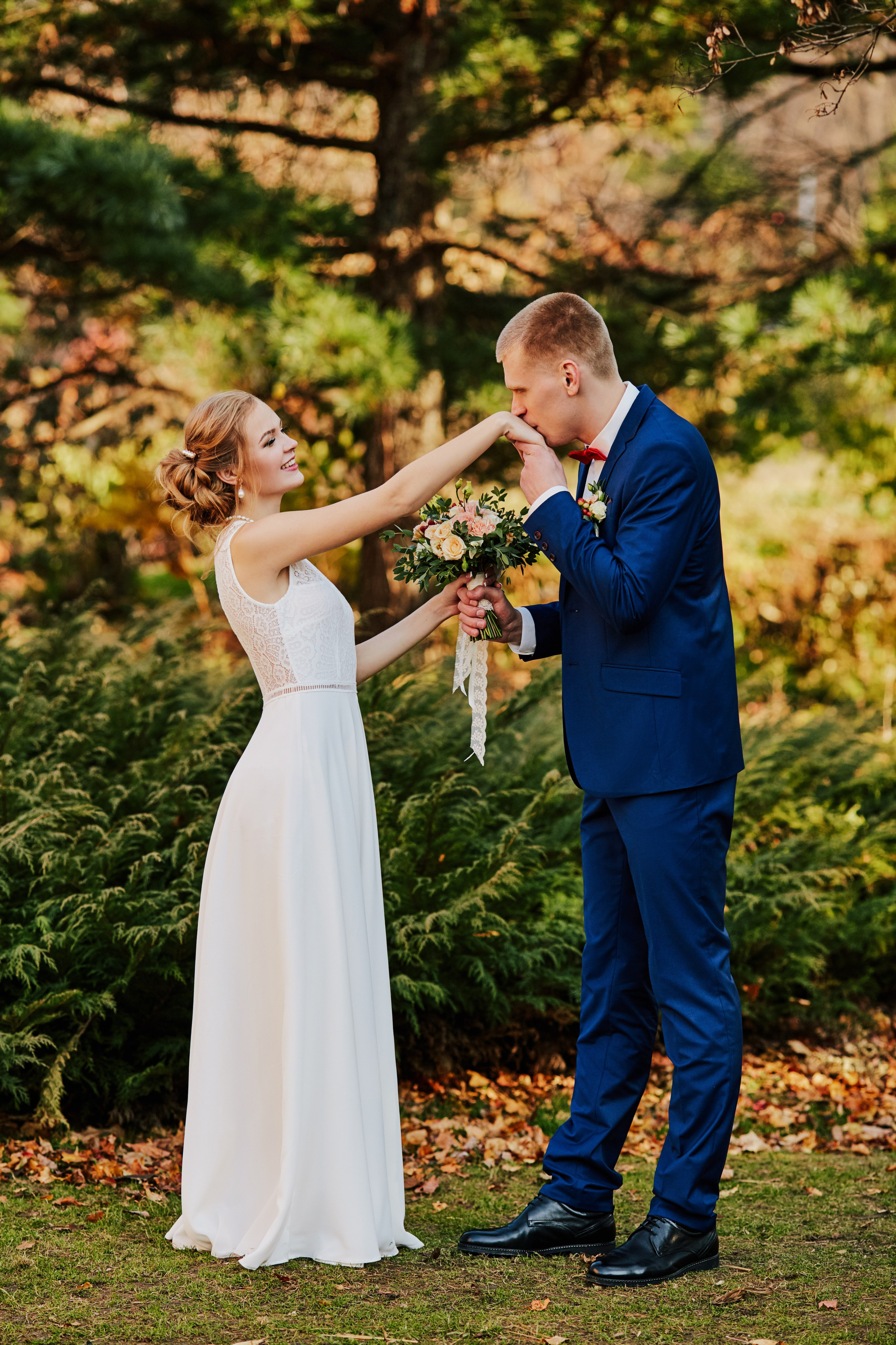 Жених целует руку невесты в осеннем парке во Владивостоке