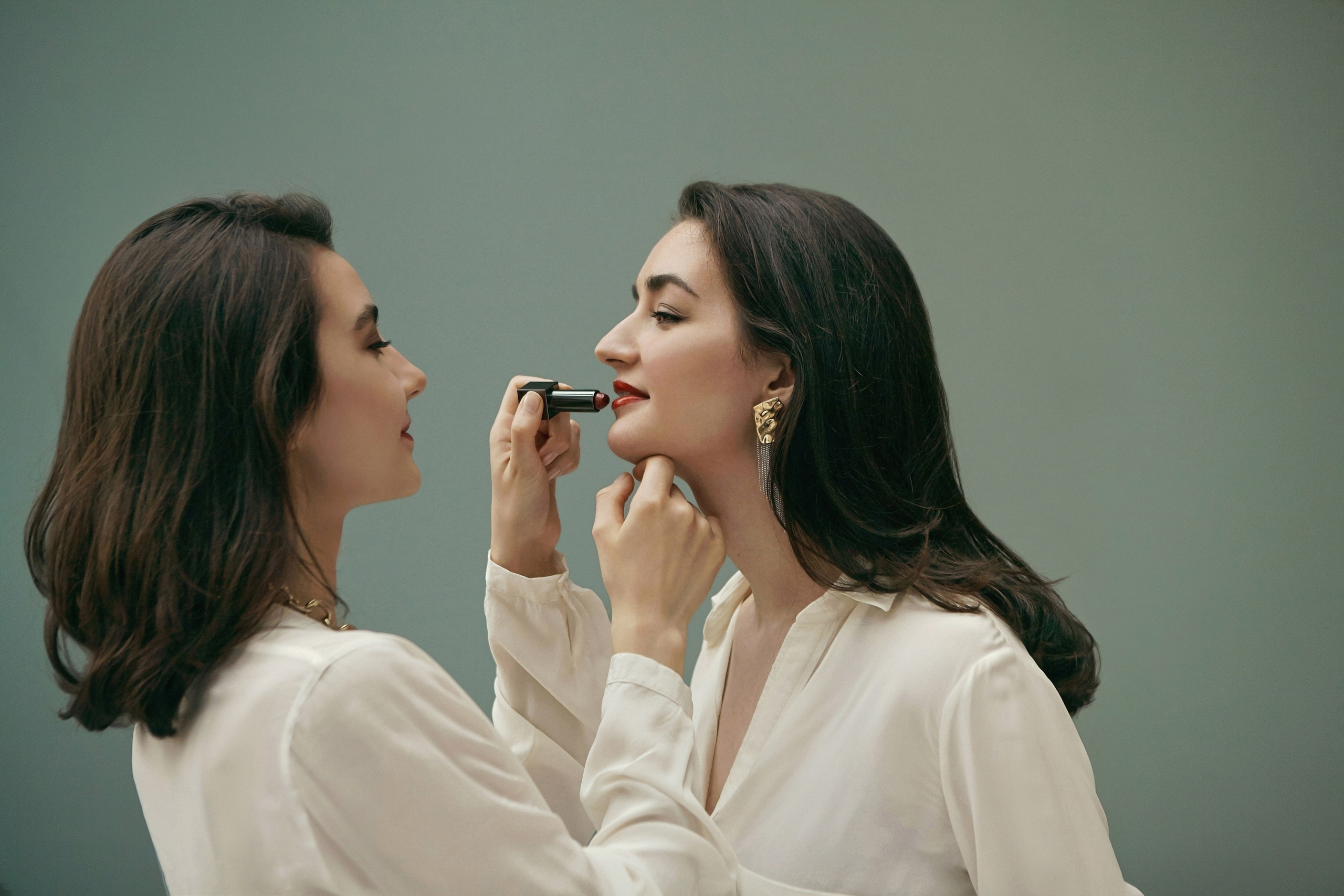 одна девушка красит красной помадой другую девушку