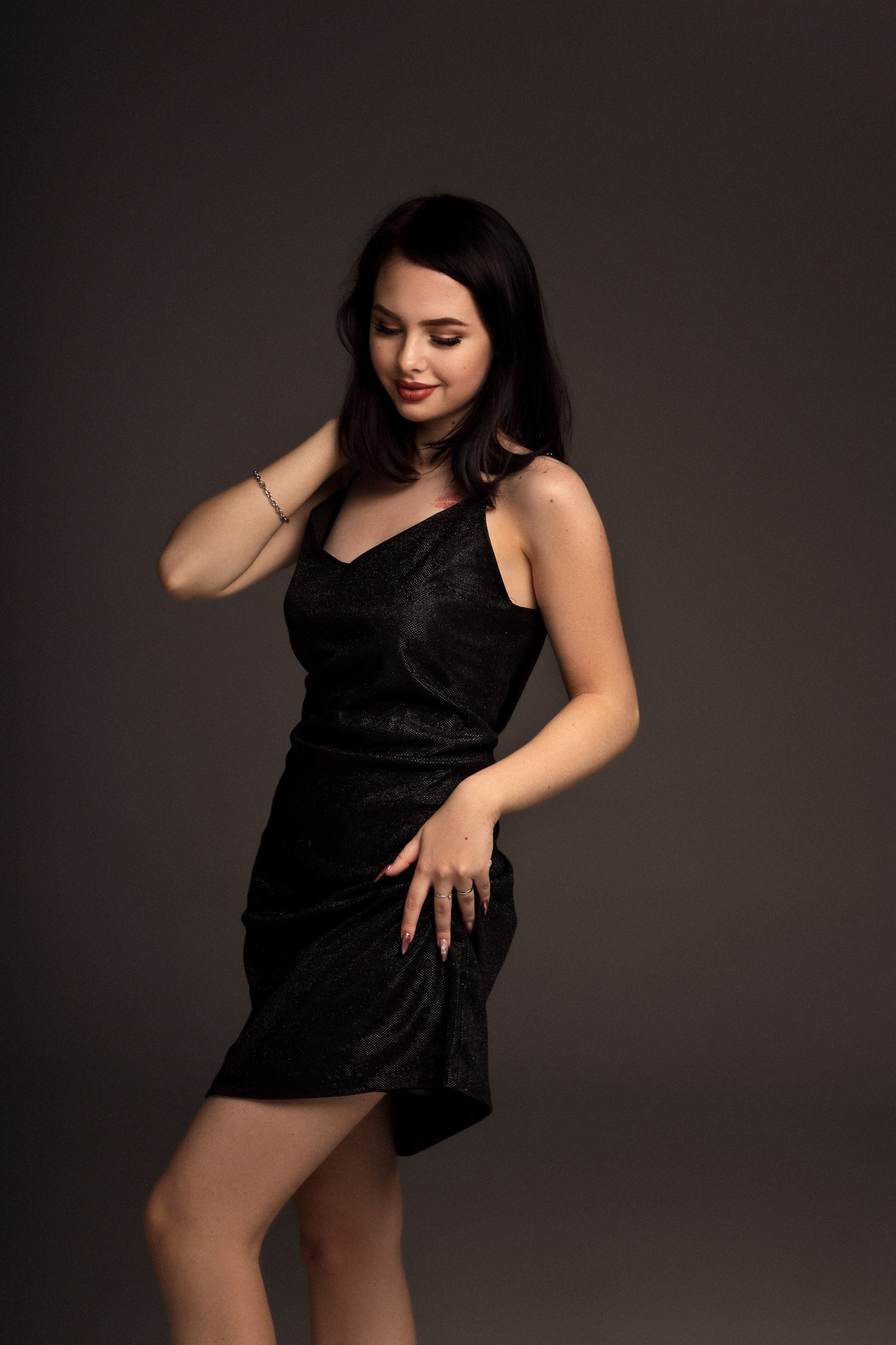 Девушка в чёрном платье танцует с улыбкой — пример живого и эмоционального кадра в женской фотосессии.