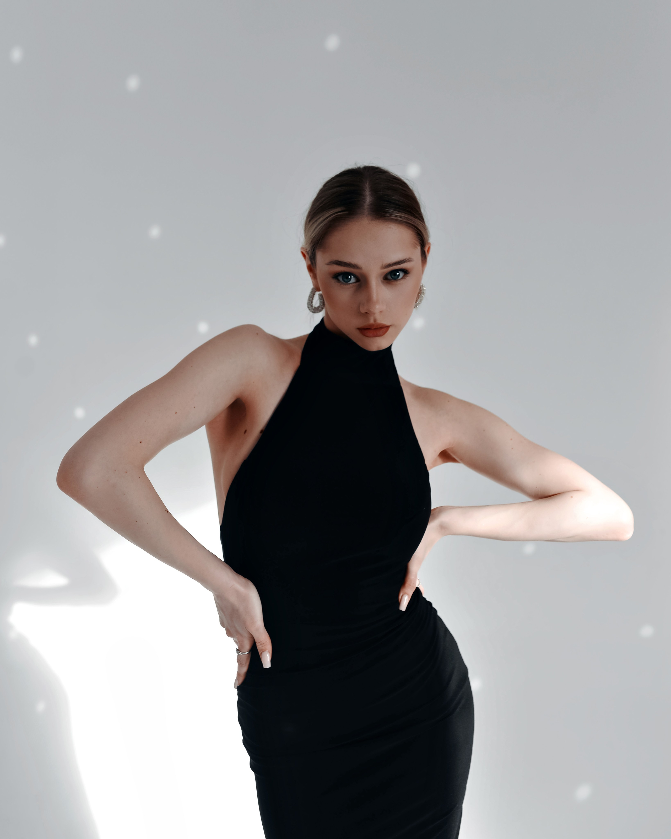 Крупный портрет девушки, которая позирует в студии с акцентом на линиях тела