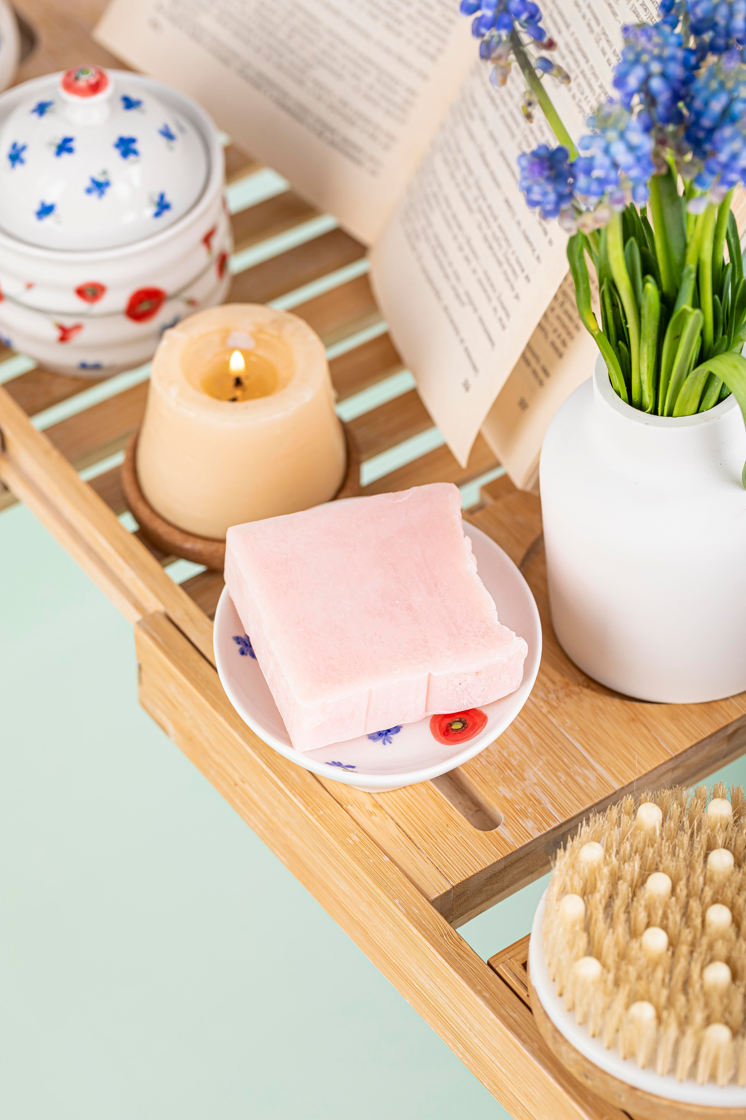 Натуральное кусковое мыло в интерьере ванный комнаты свежие цветы, горящая свеча