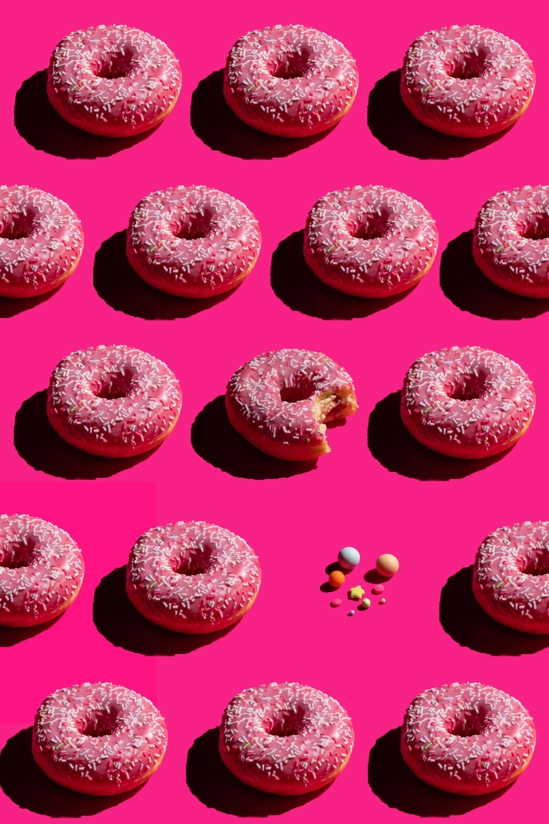 Паттерн пончиков с глазурью и посыпкой на ярком розовом фоне 