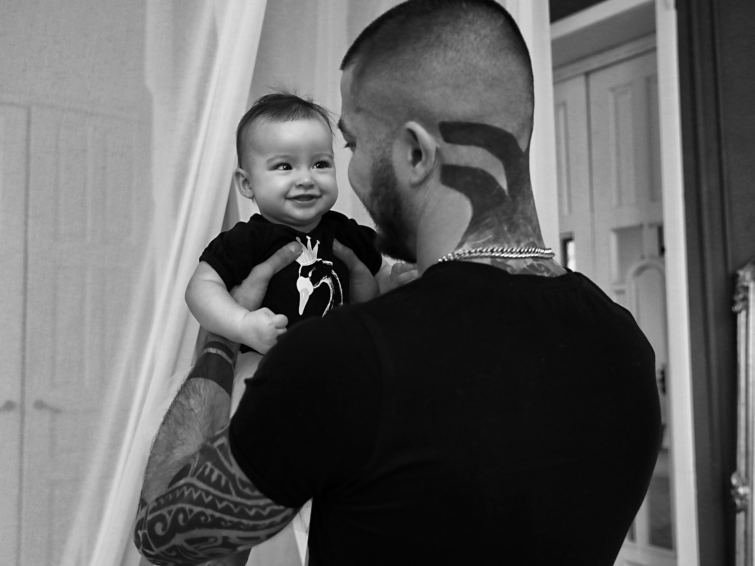Папа с тату на шее держит дочку на руках
