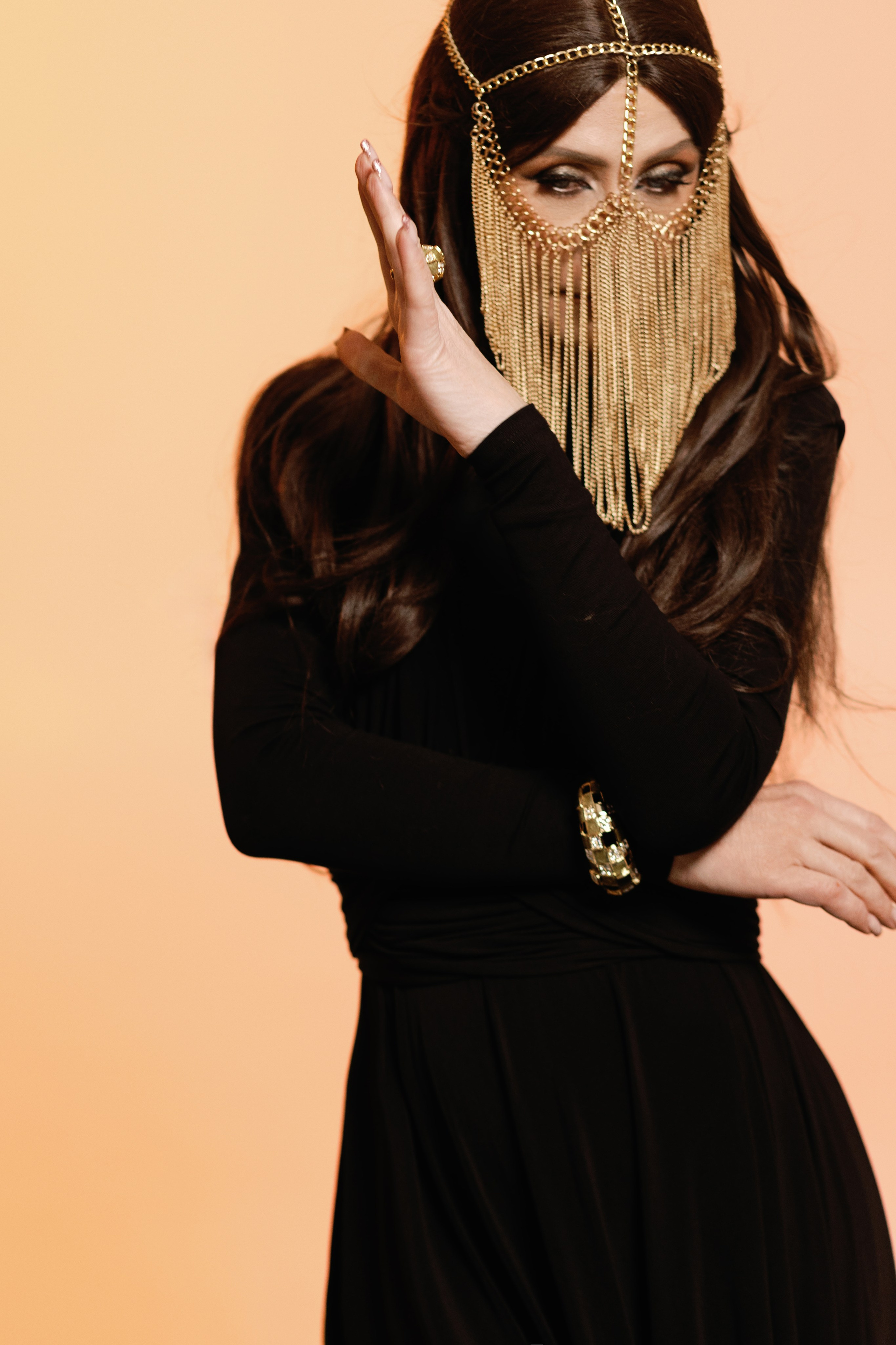 На фотографии изображена девушка c восточными украшениями на лице и в черном платье в сутдии, фотосессия в восточном стиле