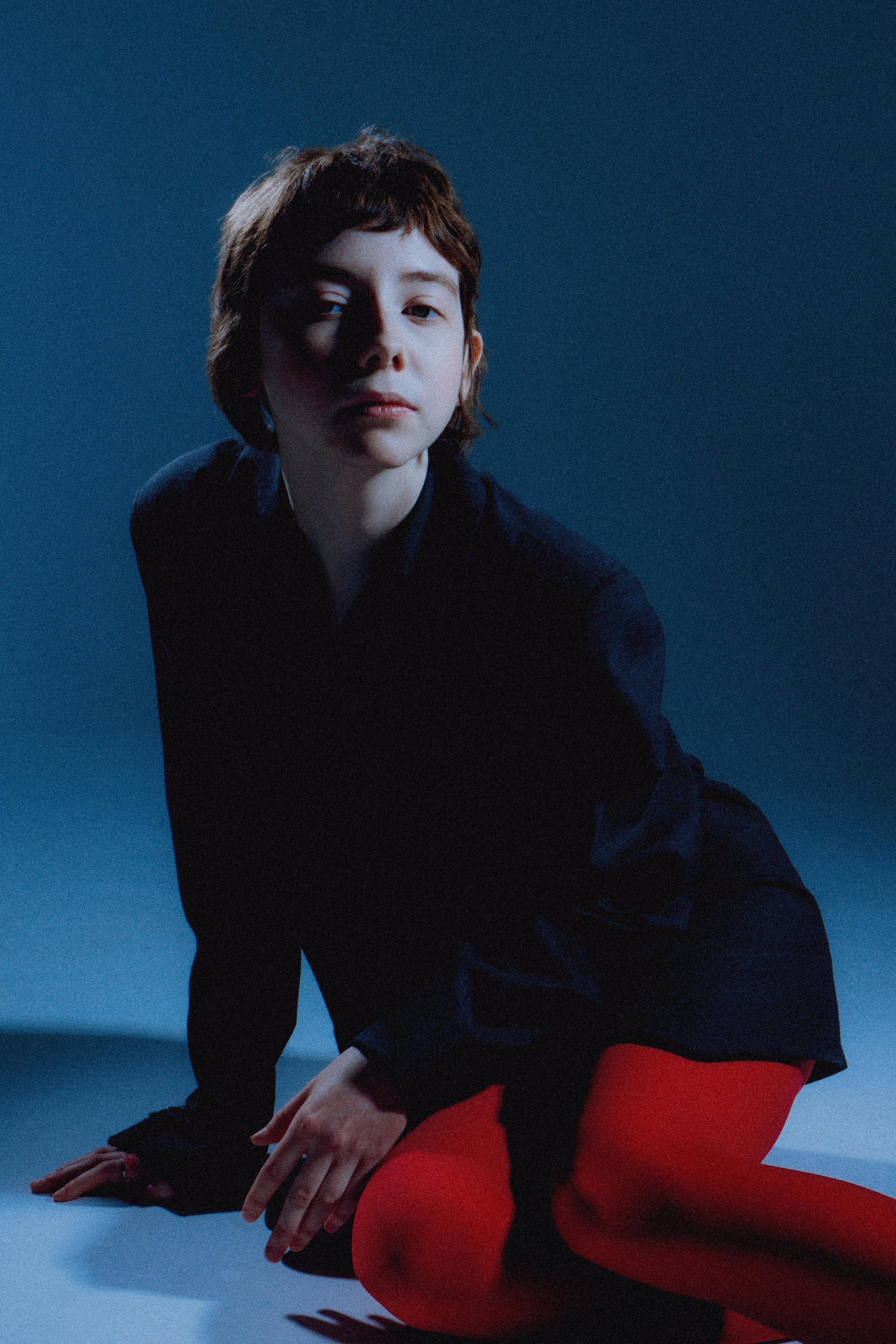 Фотомодель сидит на белом фоне в красных колготках