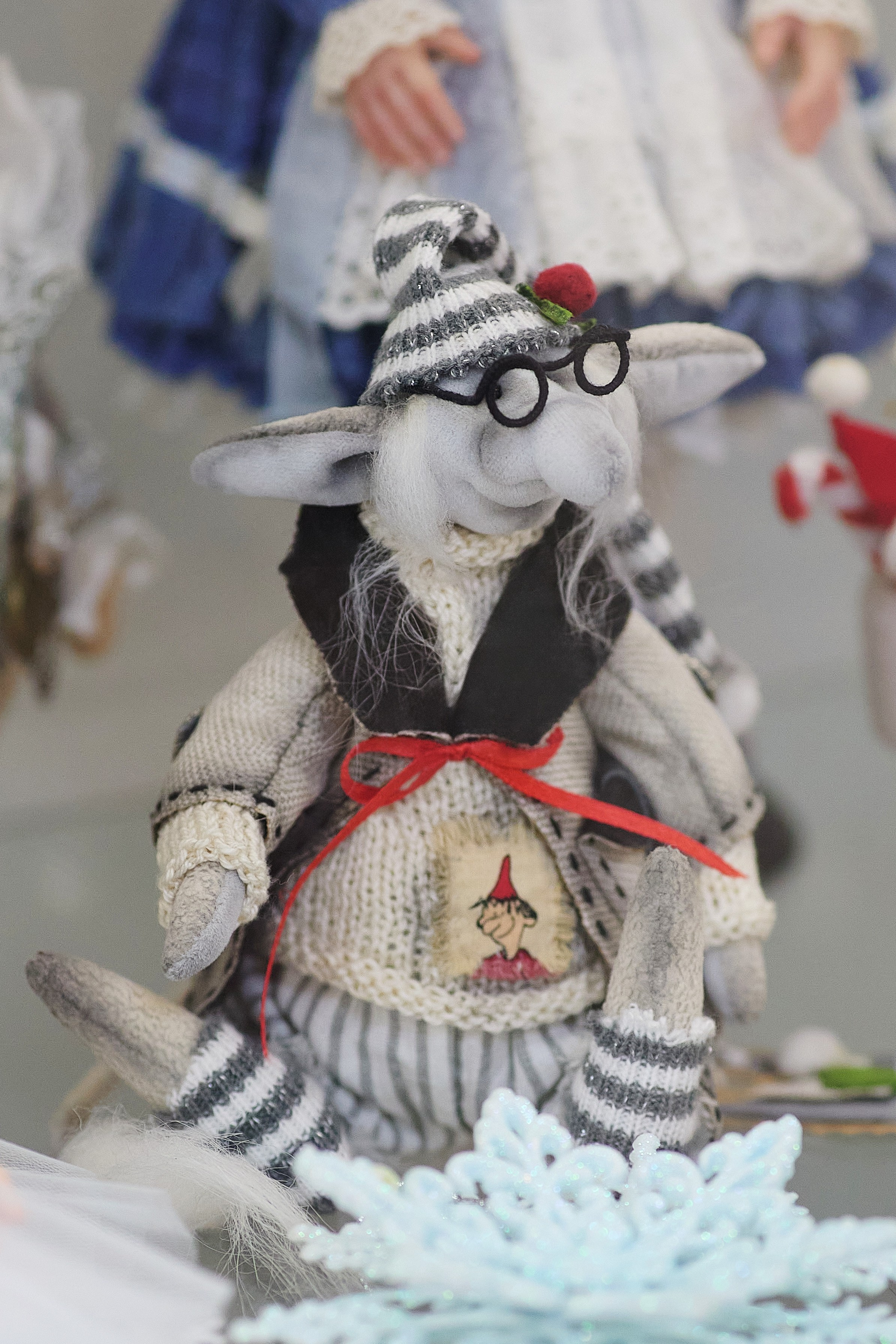 Креативная вязаная игрушка на фоне кукол и стены