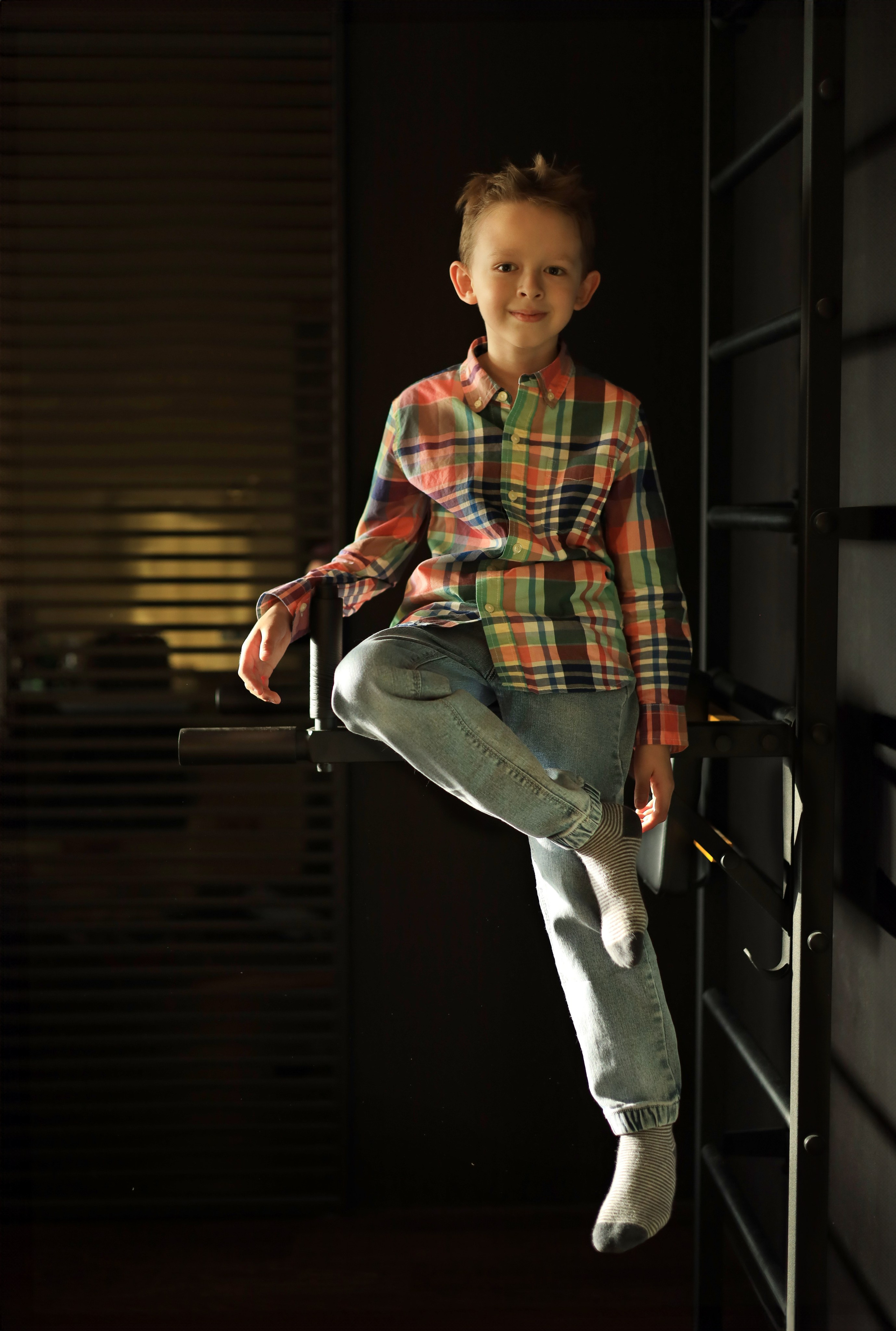 детская фотосессия мальчик сидит улыбается в джинсах и рубашке