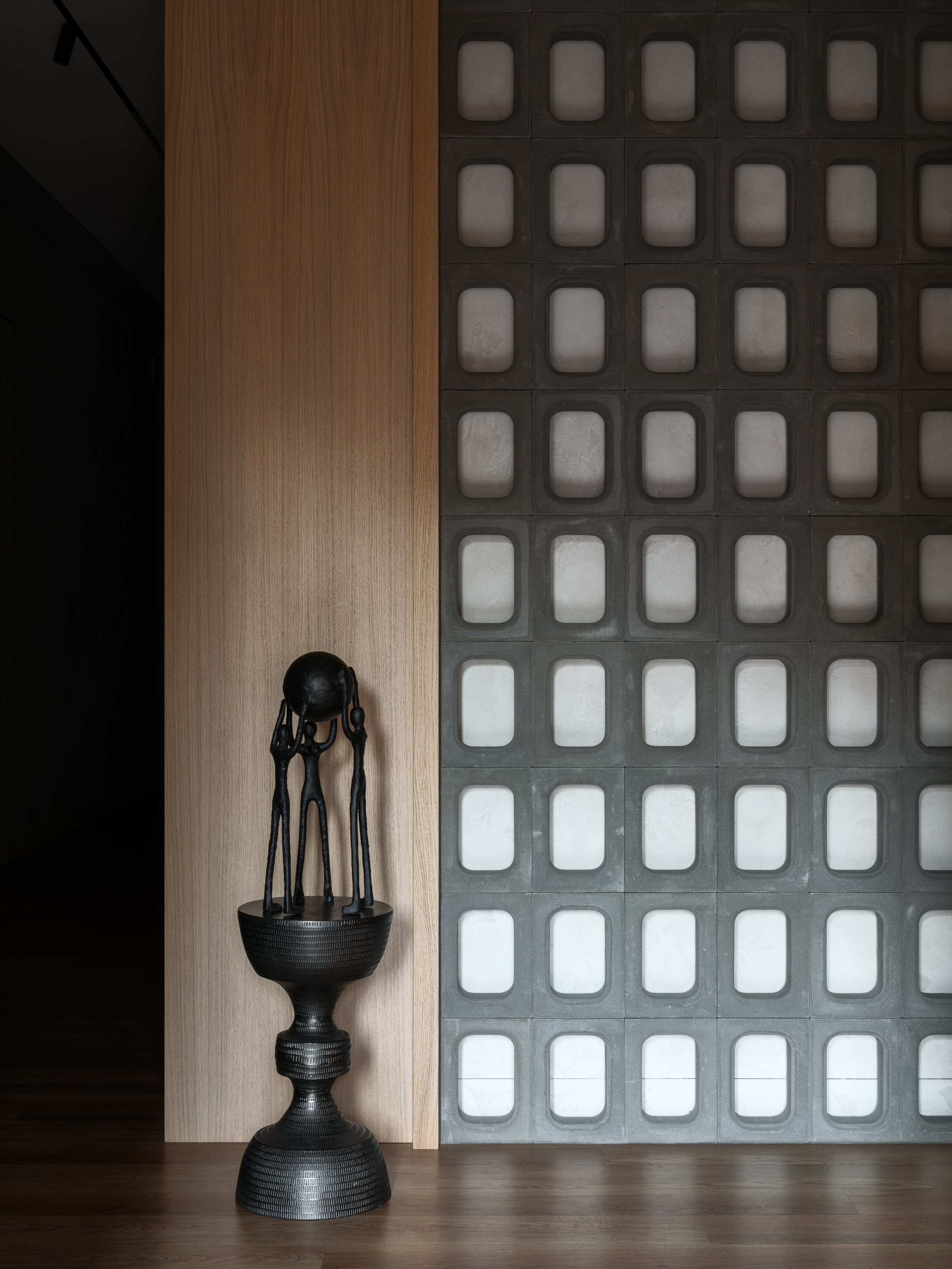 Современный акцентный угол интерьера с серой бетонной перегородкой и чёрной скульптурной композицией на фоне дерева, работа дизайнера Наталии Шелепниковой, фото Сергея Денисенко, стиль Алёны Бершацкой.