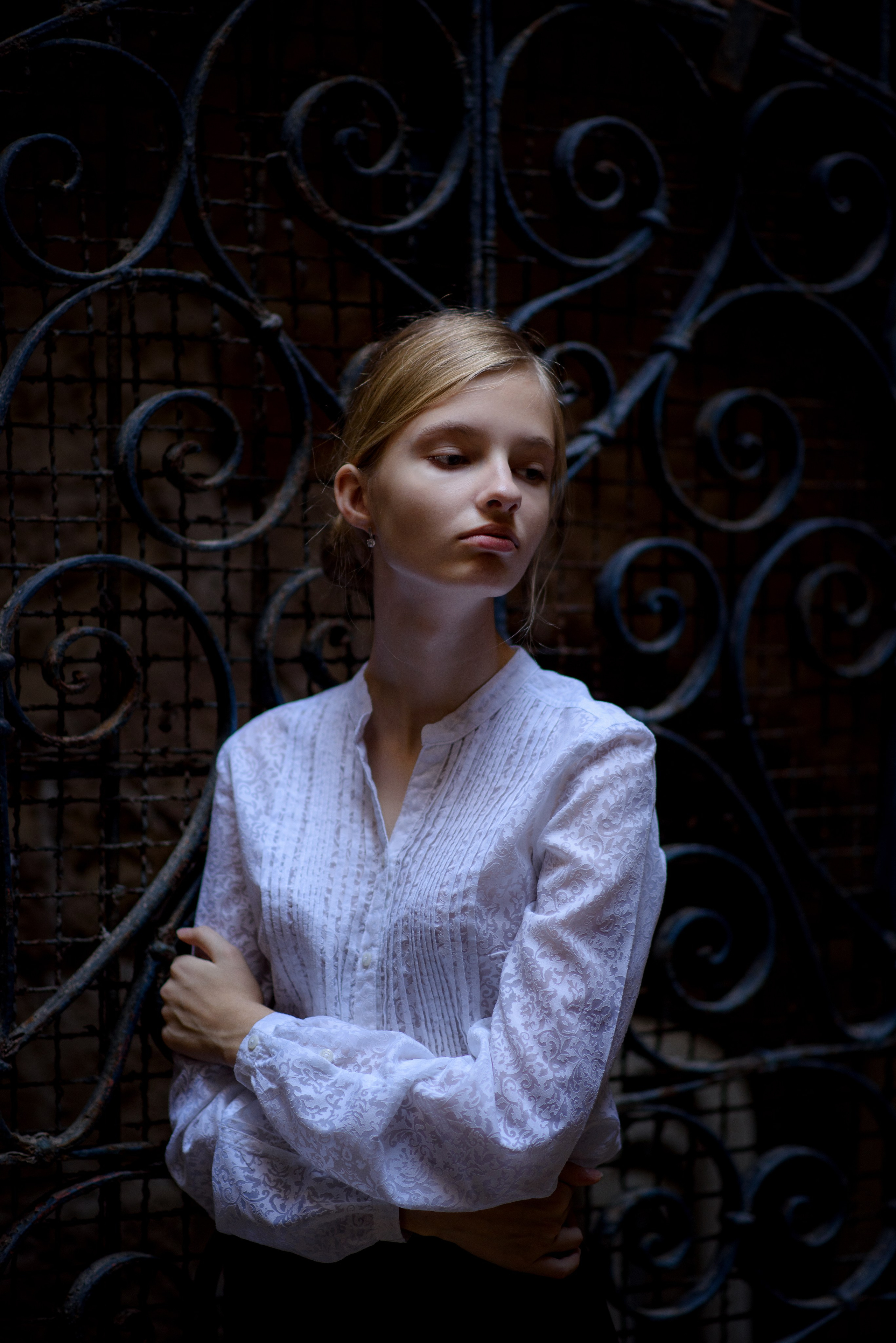 Девочка подросток на фоне старой решетки, верхний свет