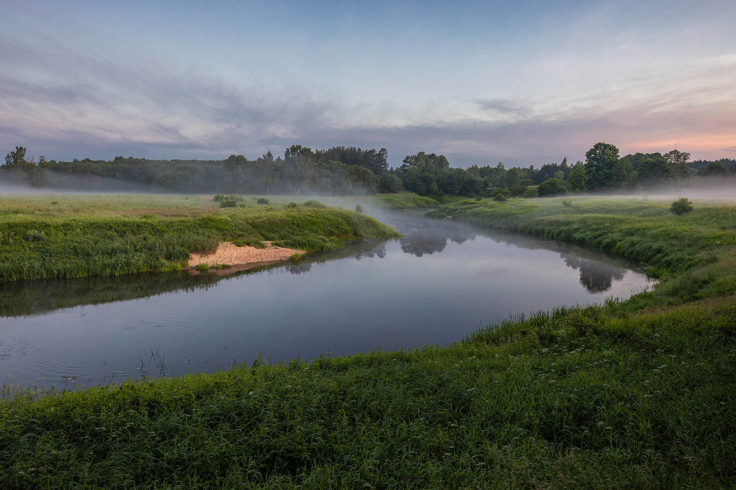 The Sheshupe River winding through lush summer meadows under a soft pastel dawn sky in East Prussia.