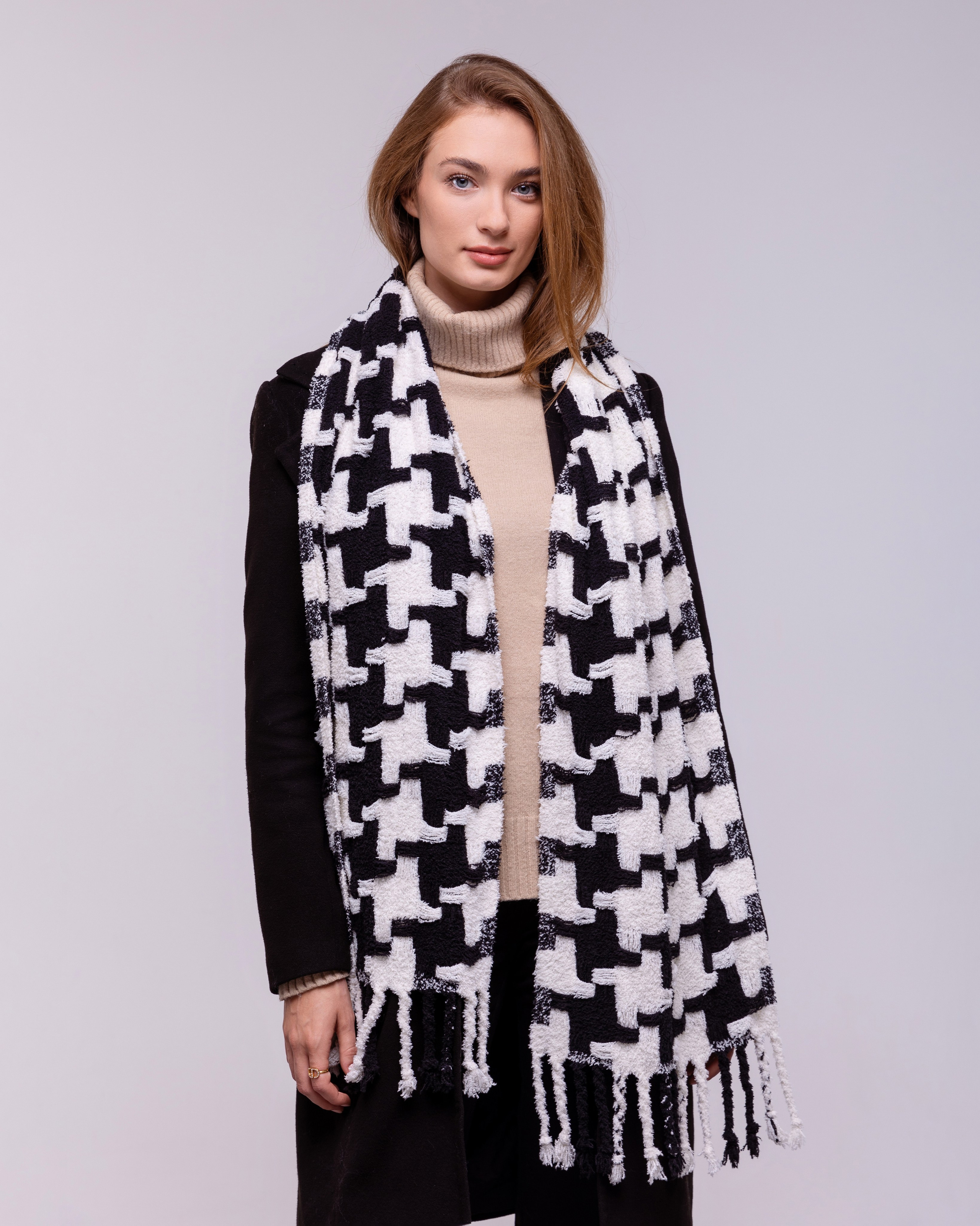 Бело-черный шарф накинутый на девушку очень гармонирует с черным пальто. 