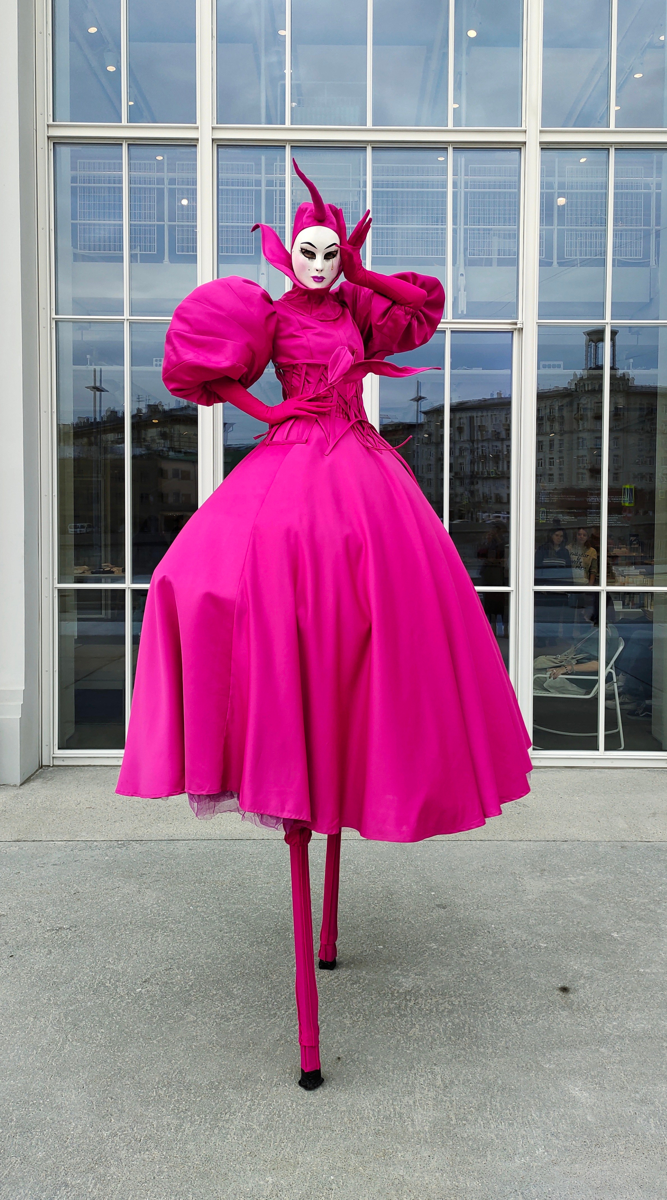 Ходулист на свадебном раусе стоит у большого витражного окна.