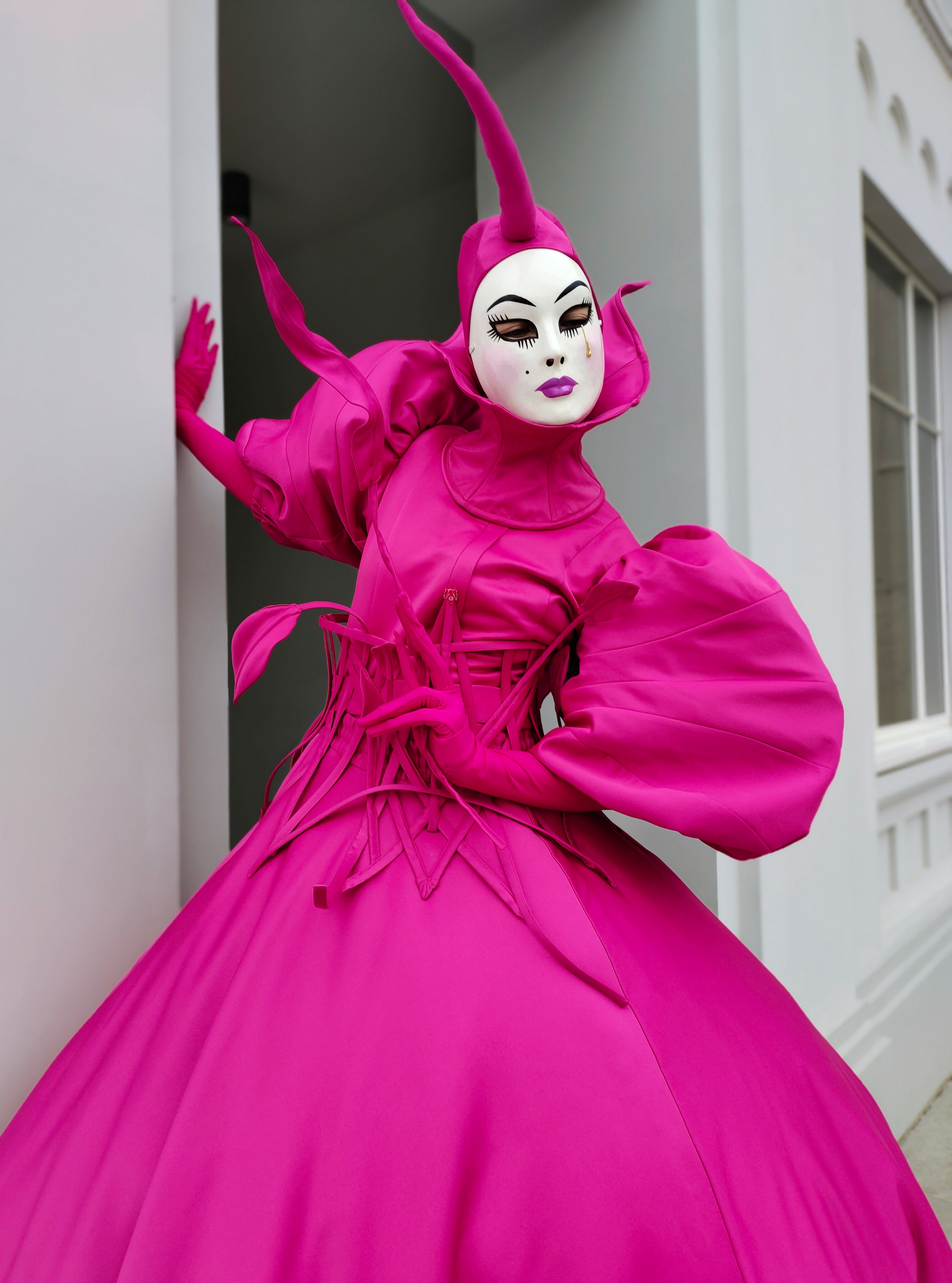 Мим от лисавлесу позирует для фотографа в костюме цвета фукси.