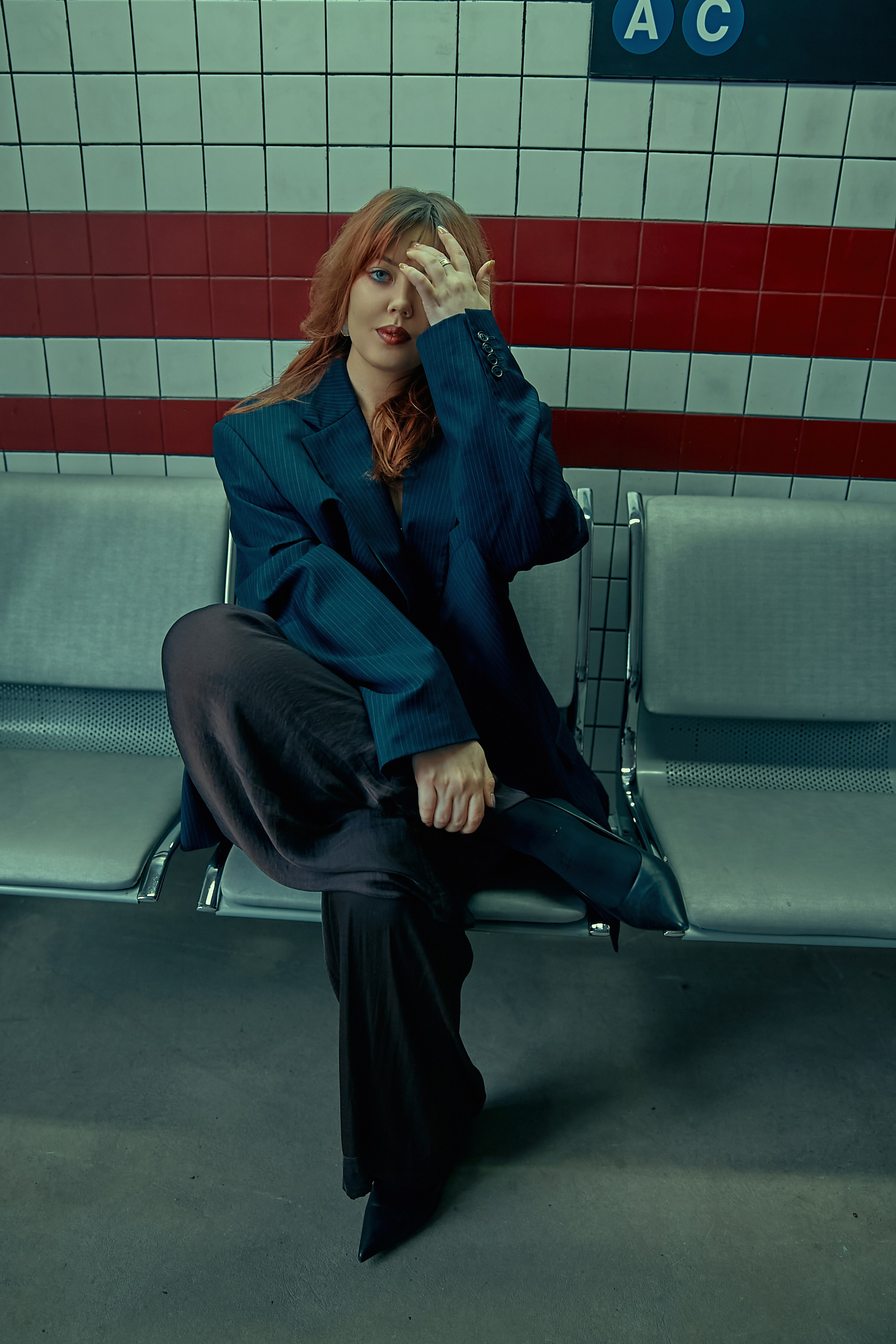 Рыжая девушка в костюме в фотостудии с интерьером Нью-Йоркского метро 