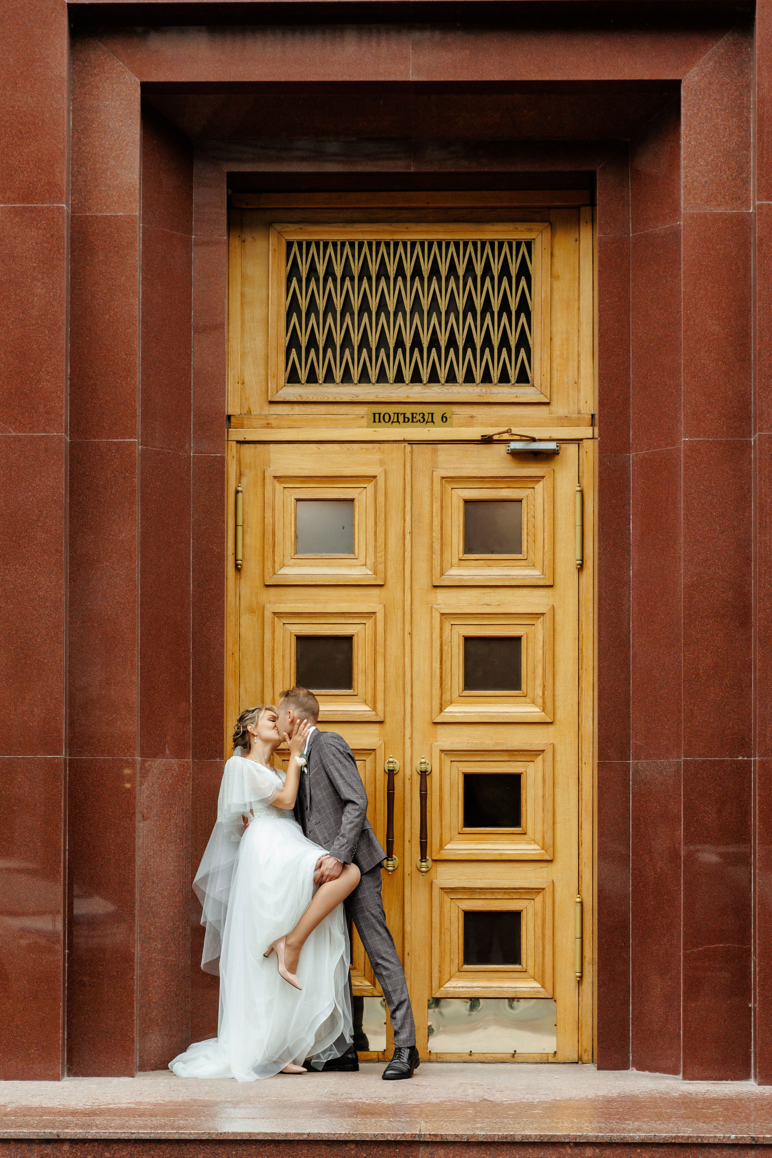 Жених и невеста фотографируются возле дверей