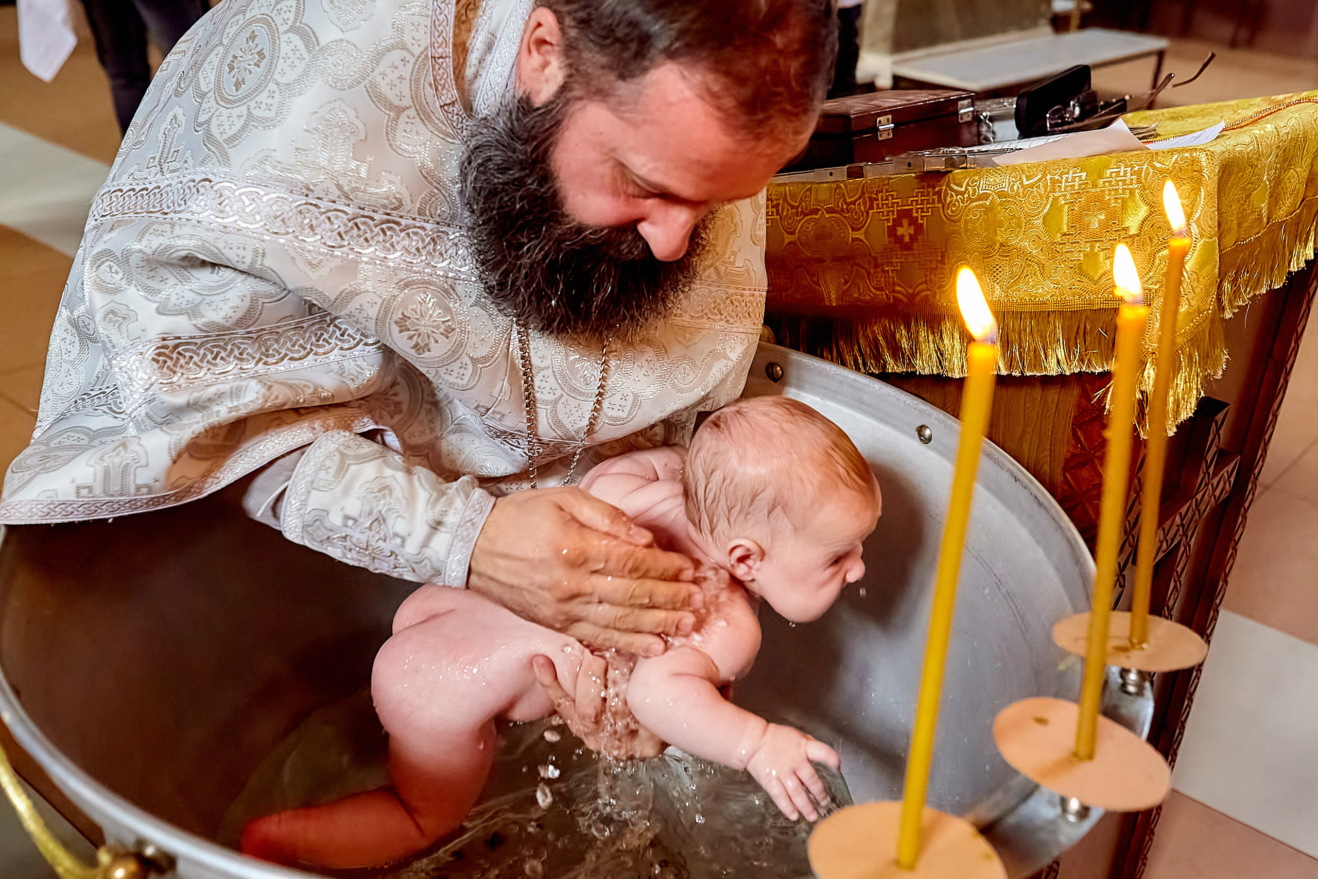 Окунание младенца в купели с водой, 