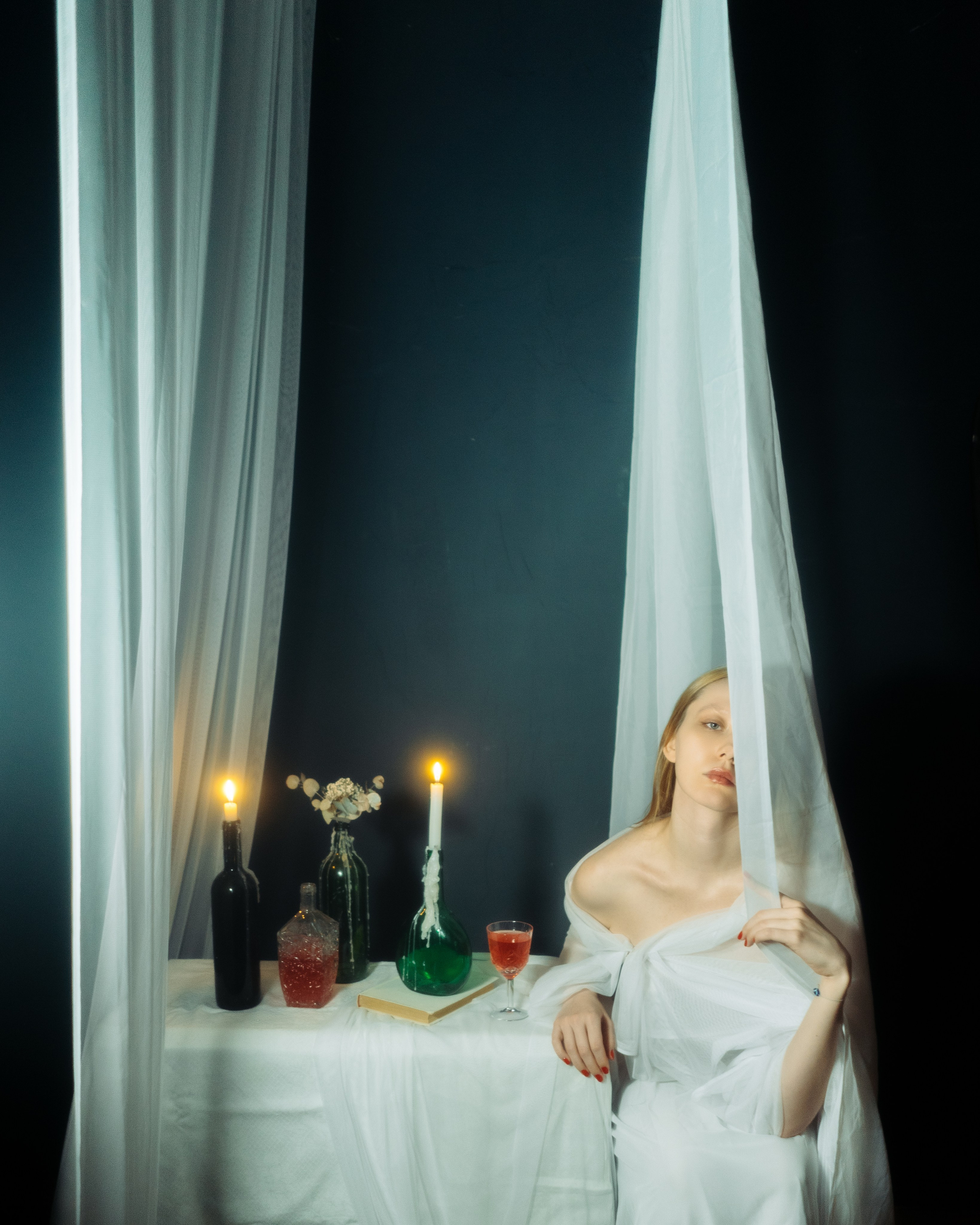 Авторская женская фотосессия в студии, девушка в белой ткани у стола со свечами, художественный портрет в темной кинематографичной эстетике