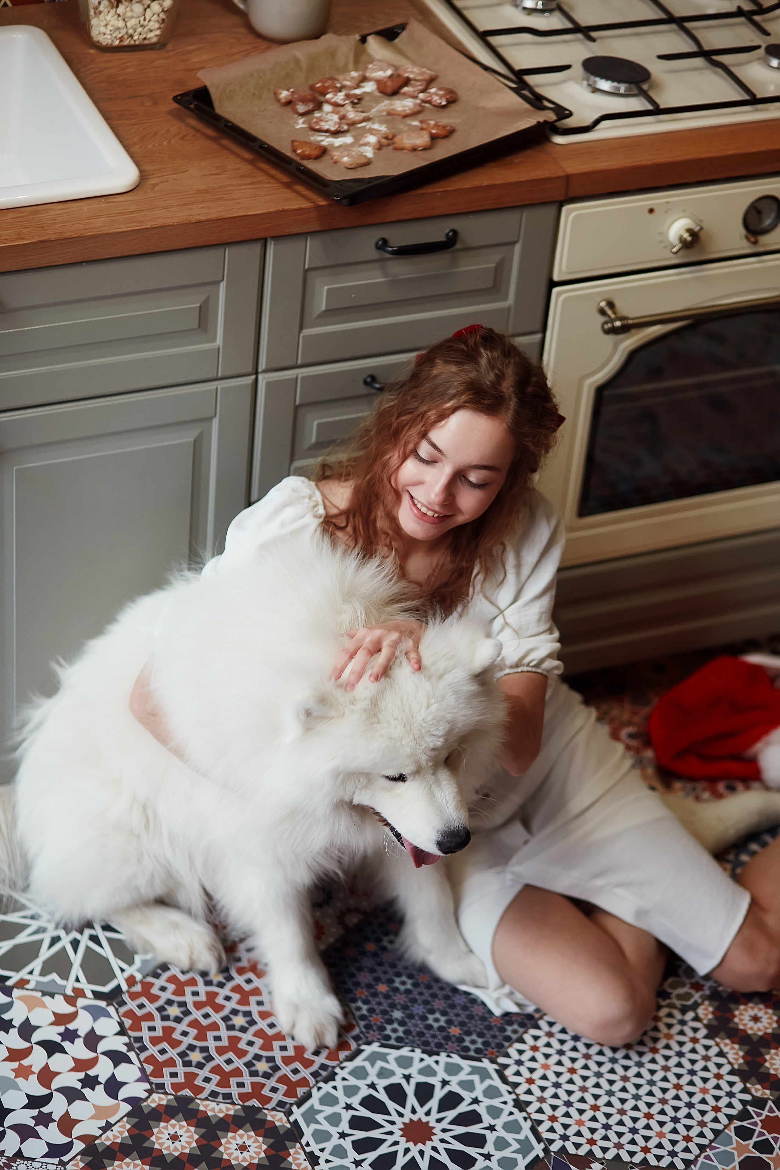 Девушка кормит собаку на полу кухни