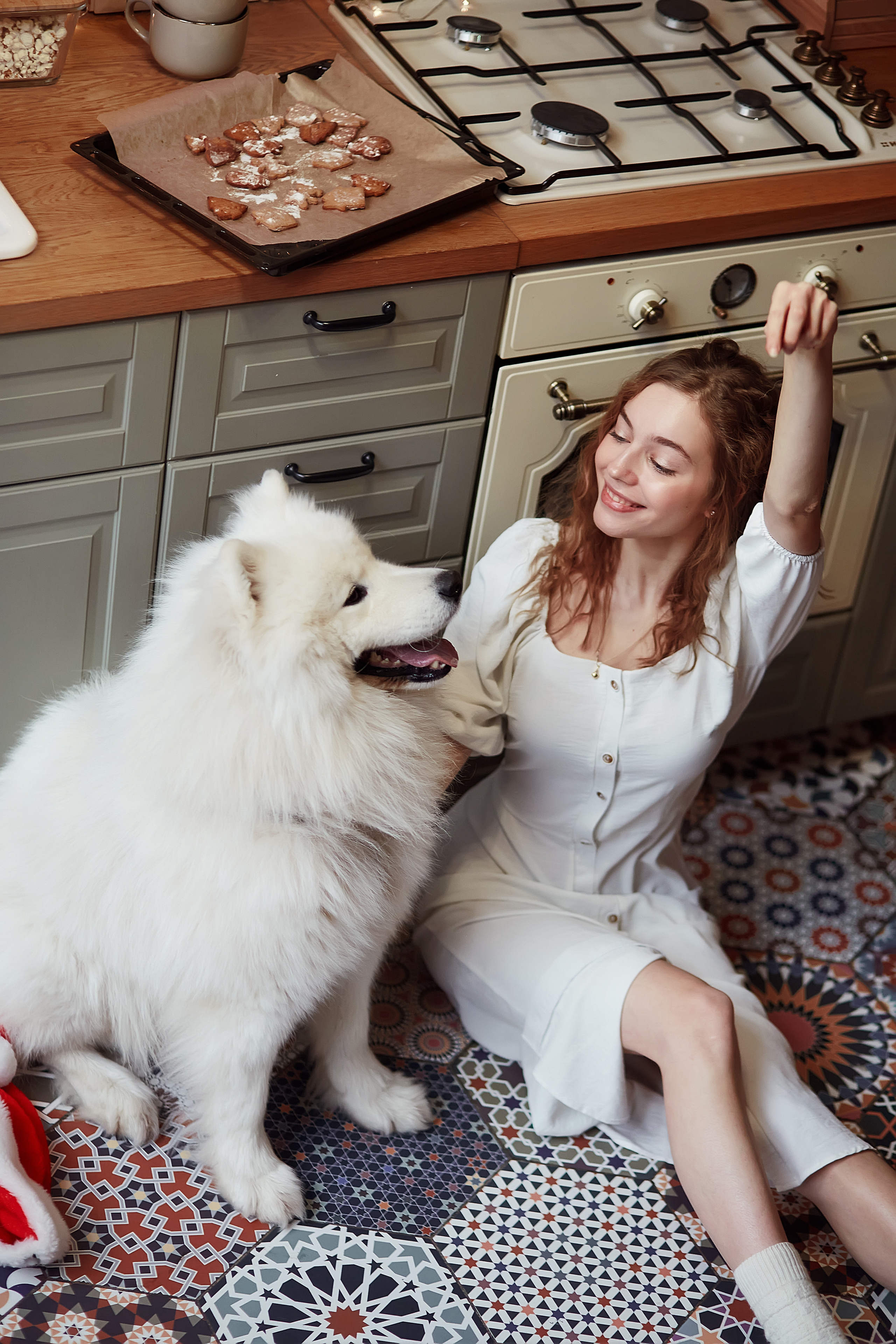 Красивая девушка, сидя на полу, подаёт команду своей собаке