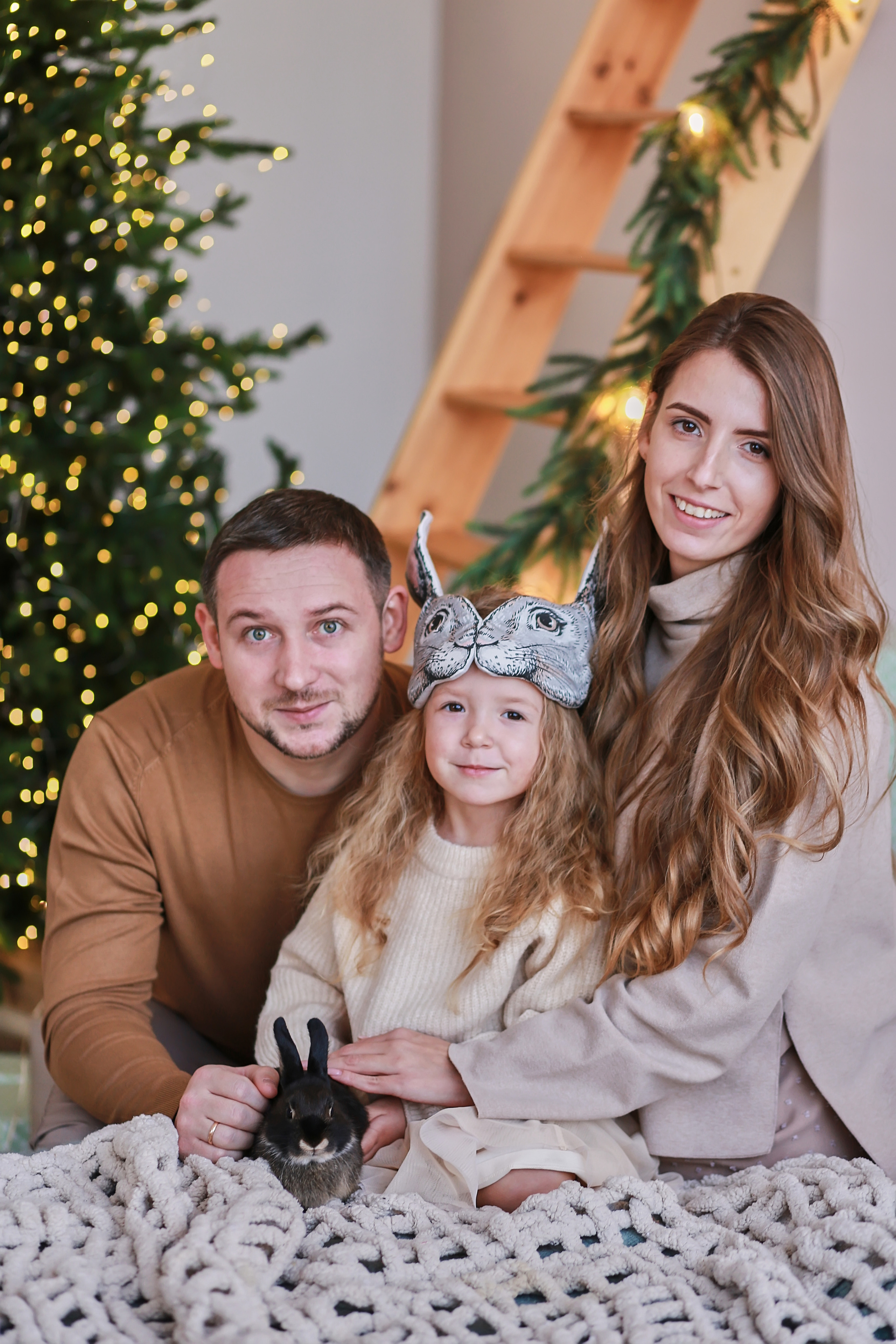 Папа, Мама и дочь сидят в комнате перед лестницей и Новогодней Елкой