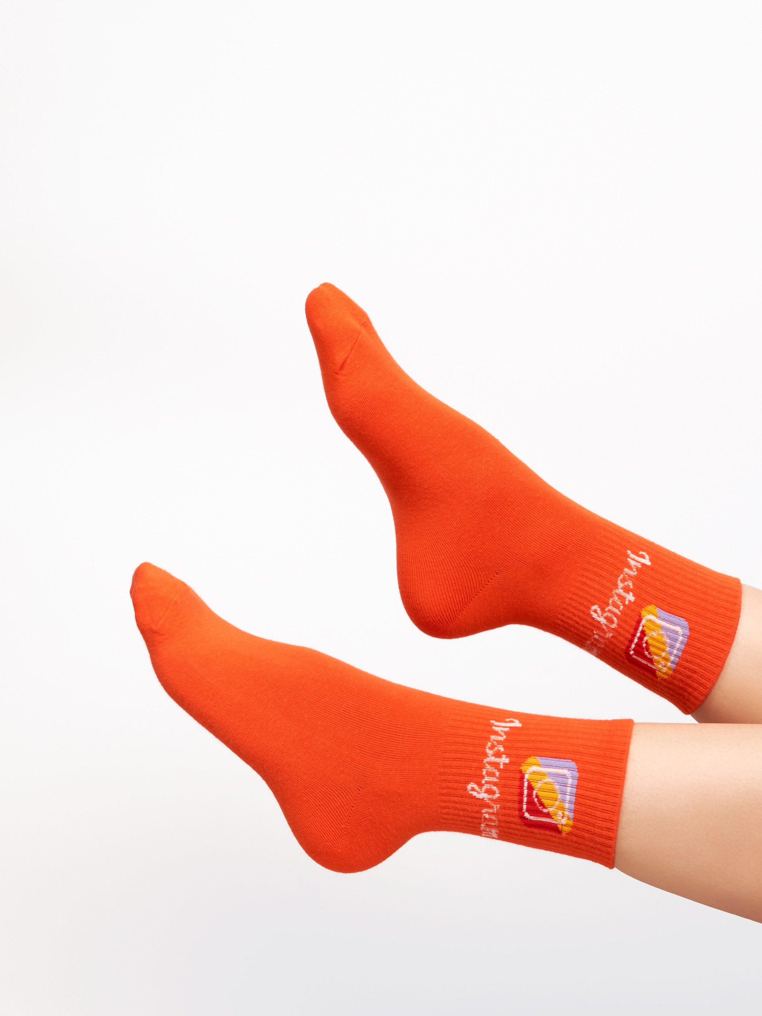 Рекламная предметная фотосъёмка оранжевых носков на ногах модели на белом фоне