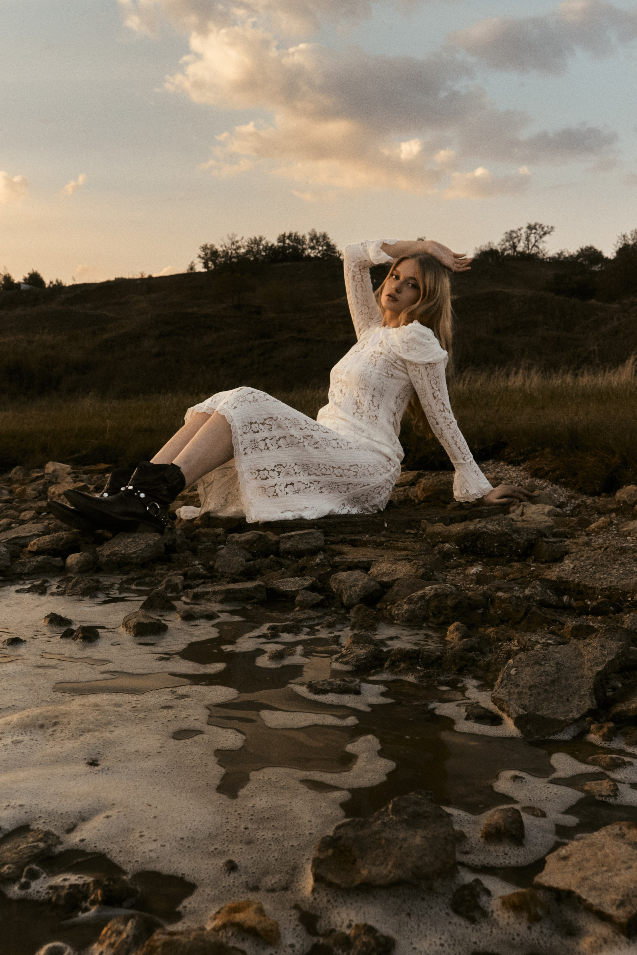 Креативная съемка у воды девушка сидит на камнях в белом платье, услуги фотографа в Ростове-на-Дону