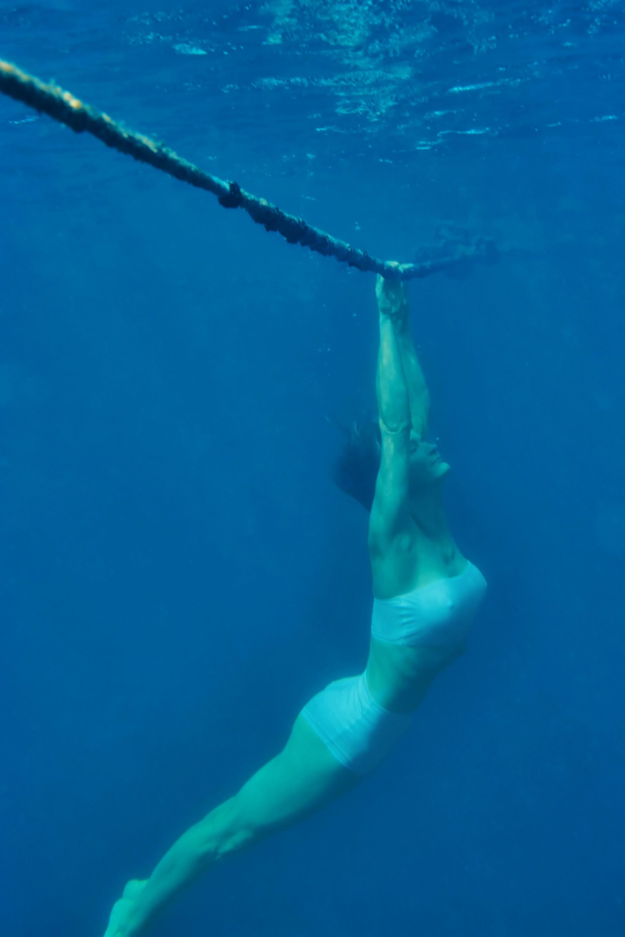 Девушка под водой держится за канат