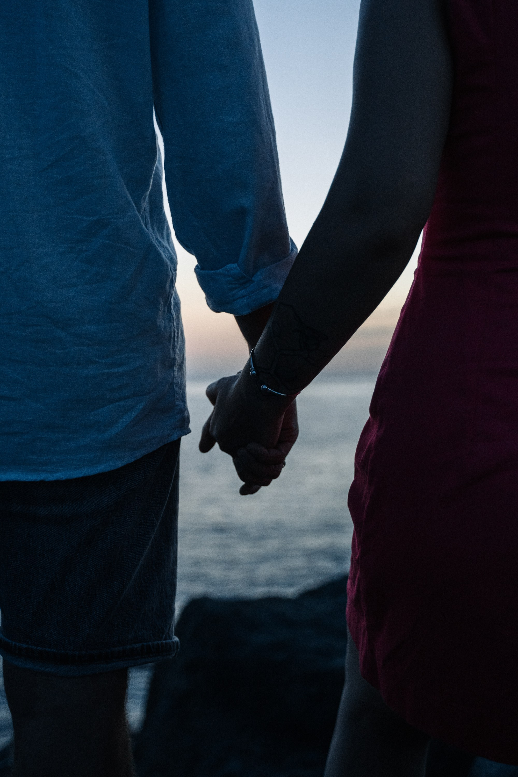 Фотография  молодой пары на фоне моря держались за руки