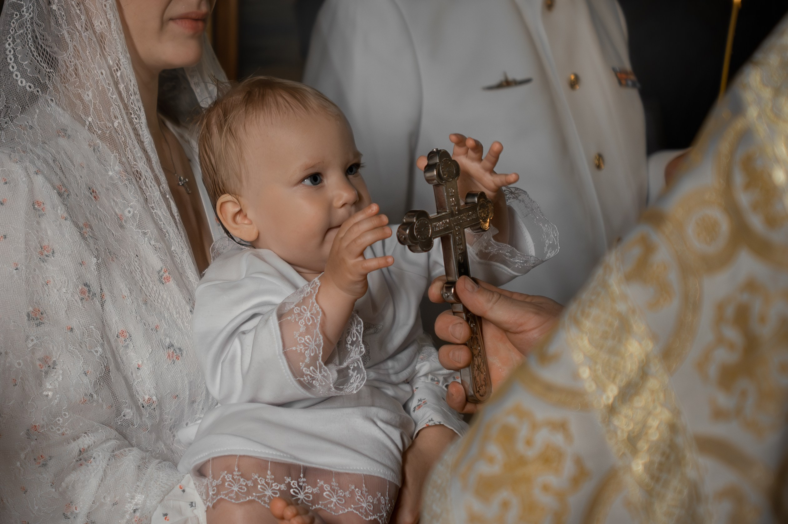 малышка держится за крест в руках батюшки