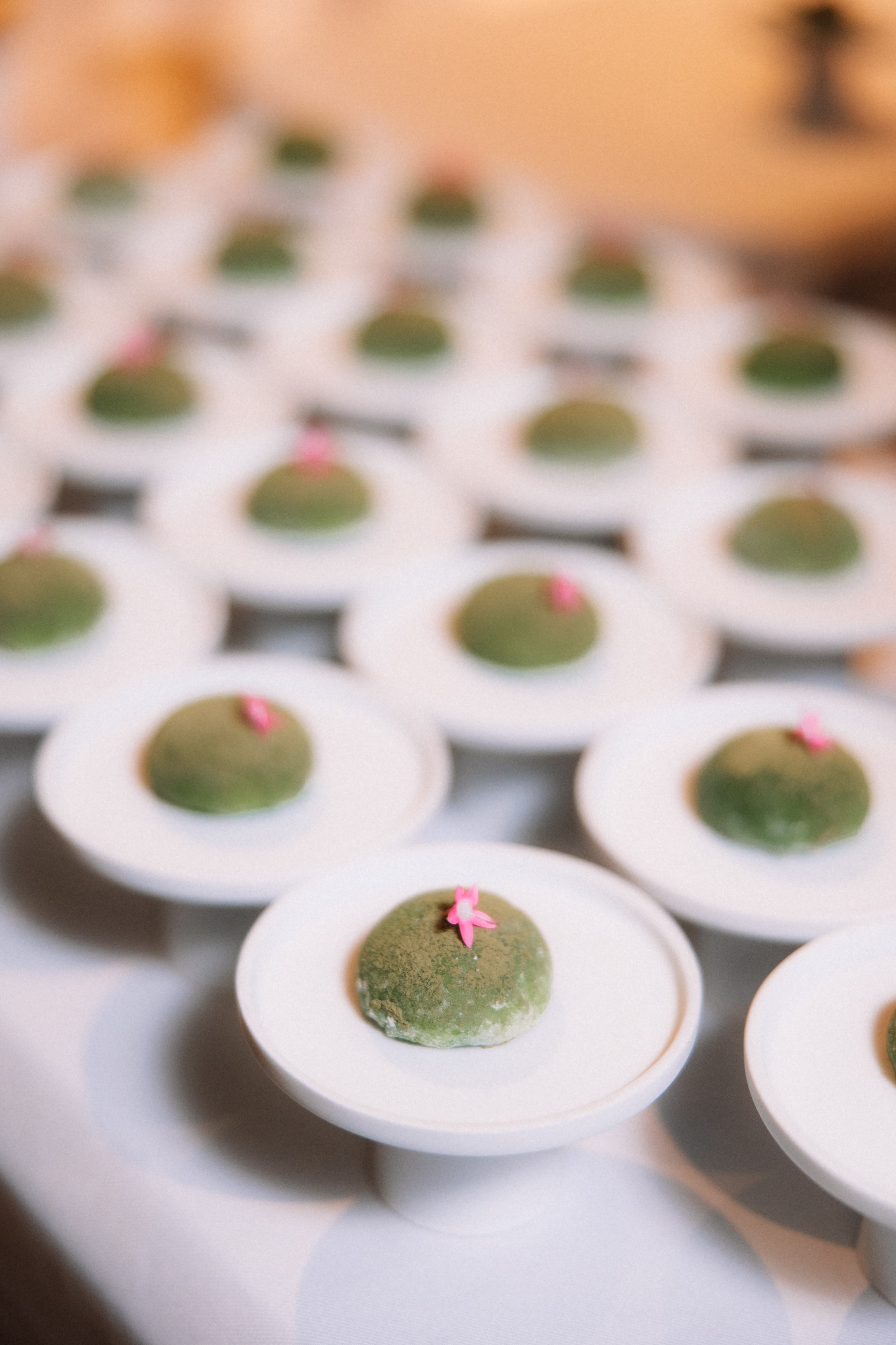 Фуршет: Длинный ряд десертов (пирожных) зеленого цвета на белых подставках.