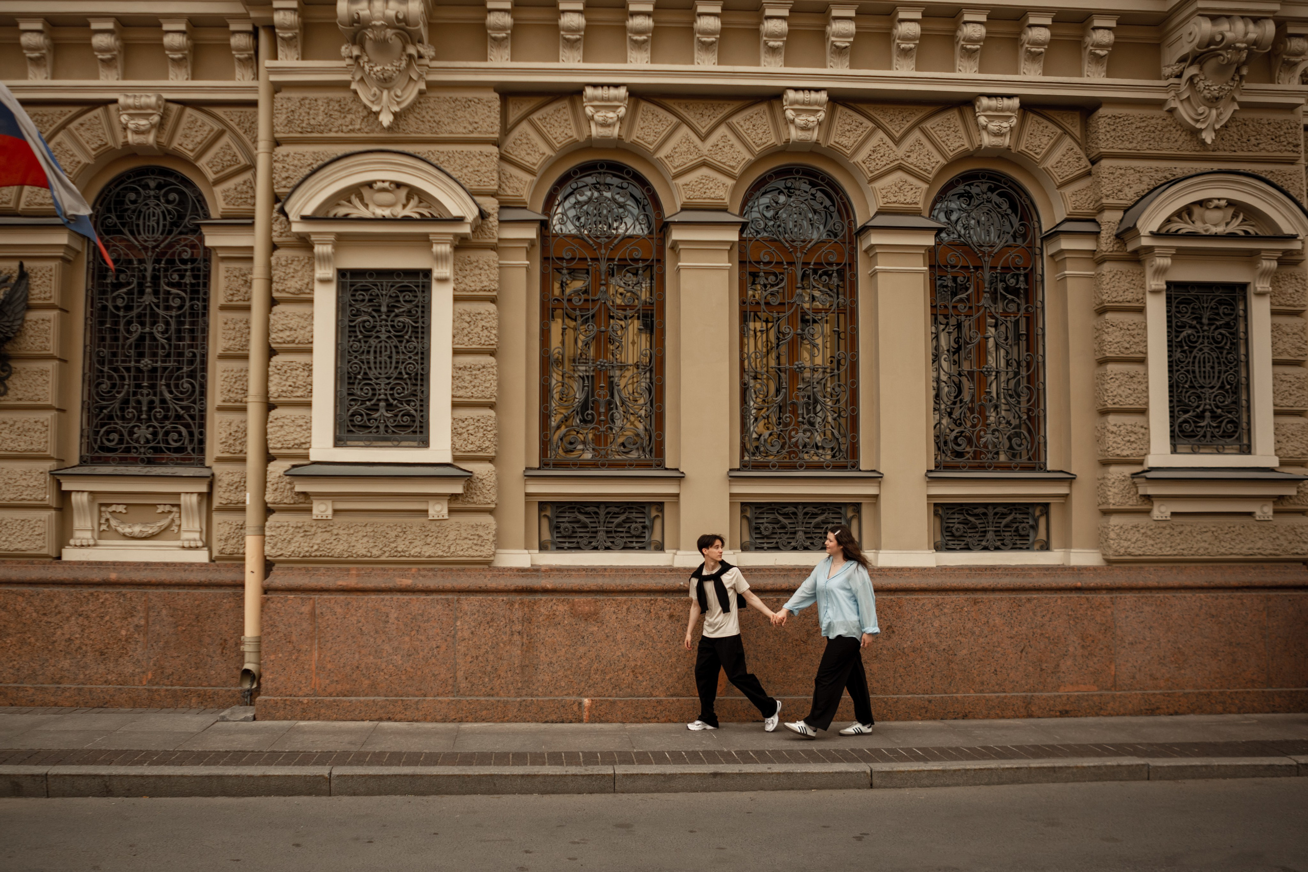 Красивый кадр на фотопрогулке лавстори: пара бежит у исторического здания.