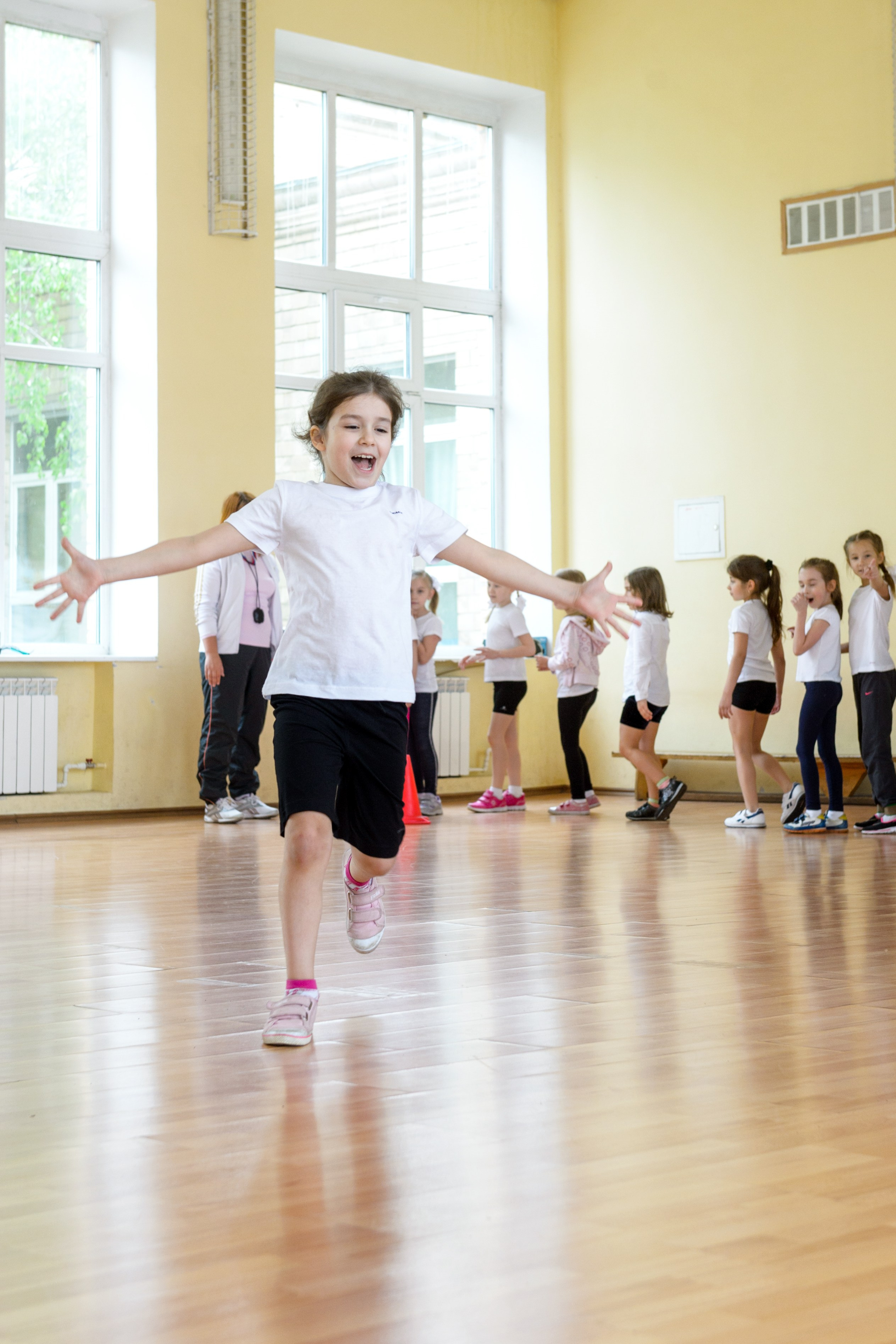 Девочка бежит по школьному спортзалу во время занятия