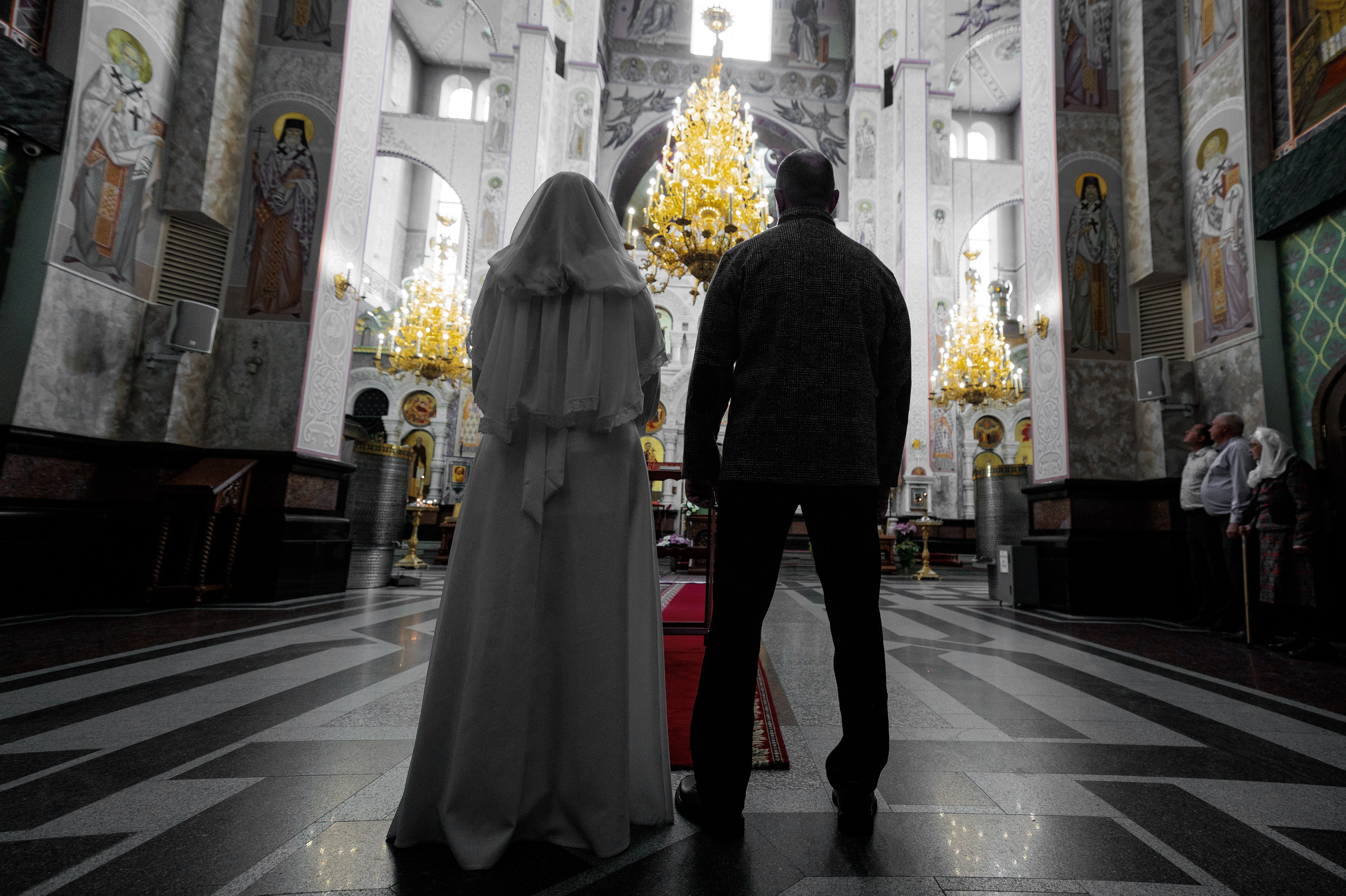 Пара входит в собор, золотые паникадила и иконостас в глубину, вид сзади — Екатеринбург, Илья Антропов