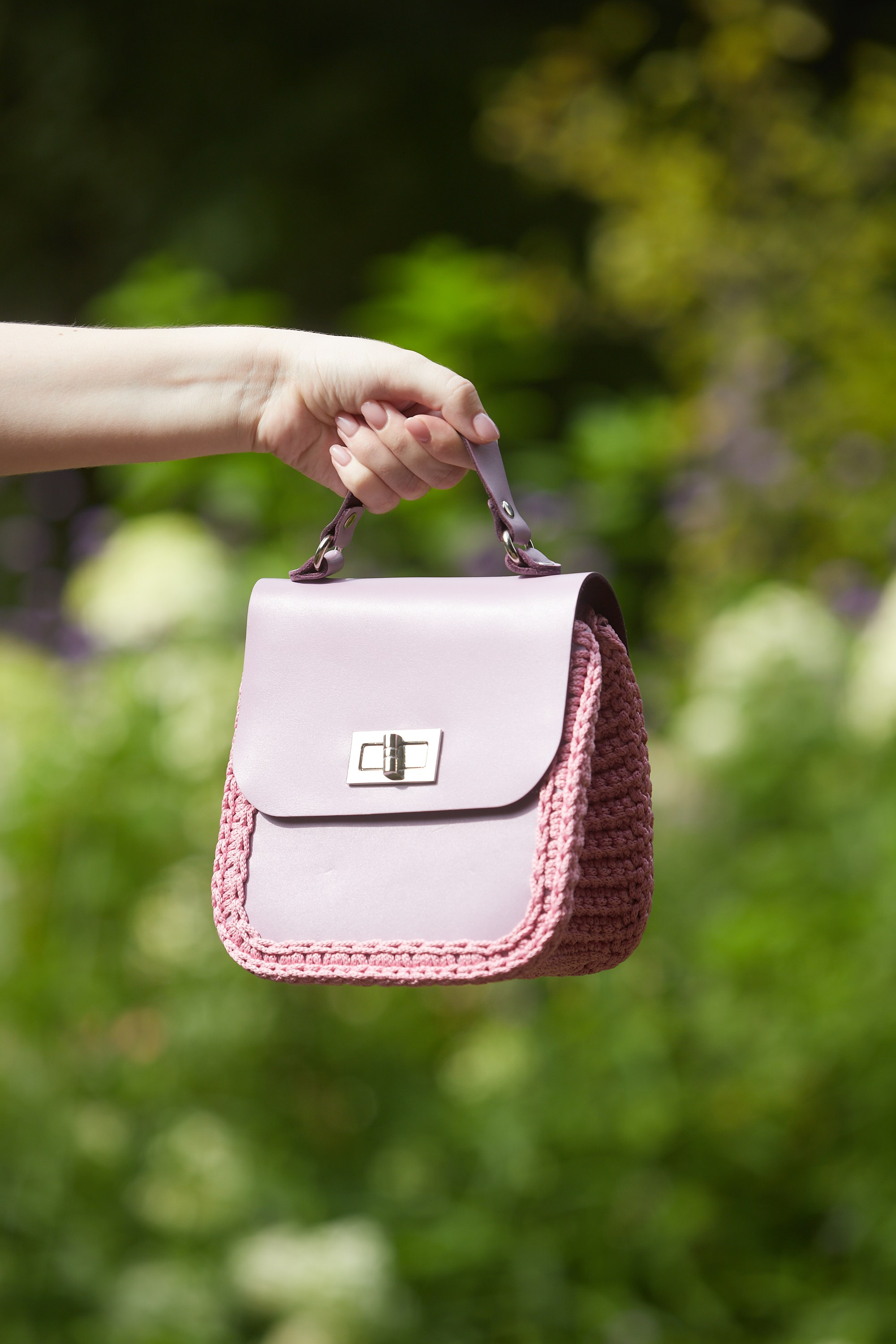 Предметная съёмка сиреневой вязаной сумки в руках модели.