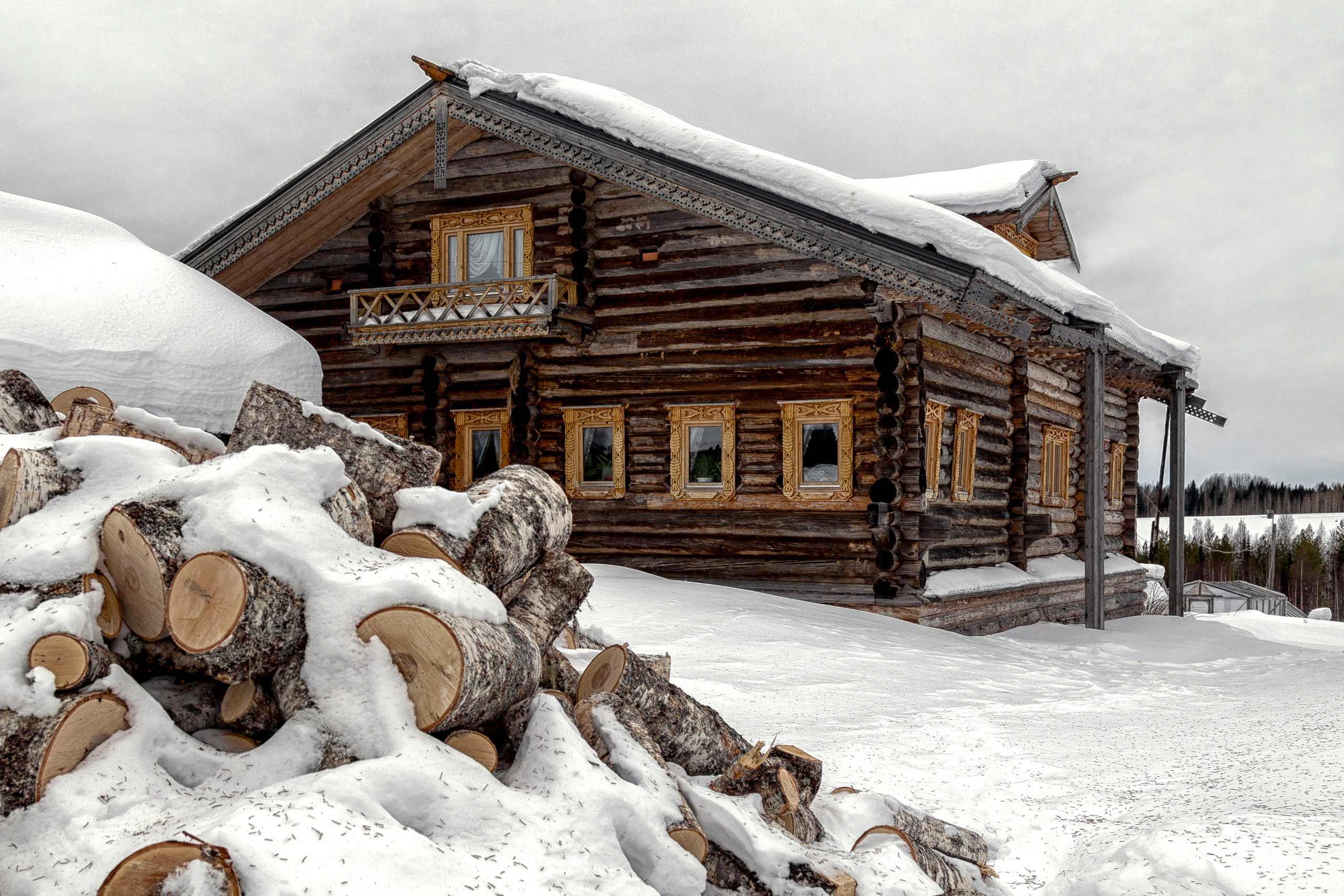 Поленница дров под снегом в деревне у дома.