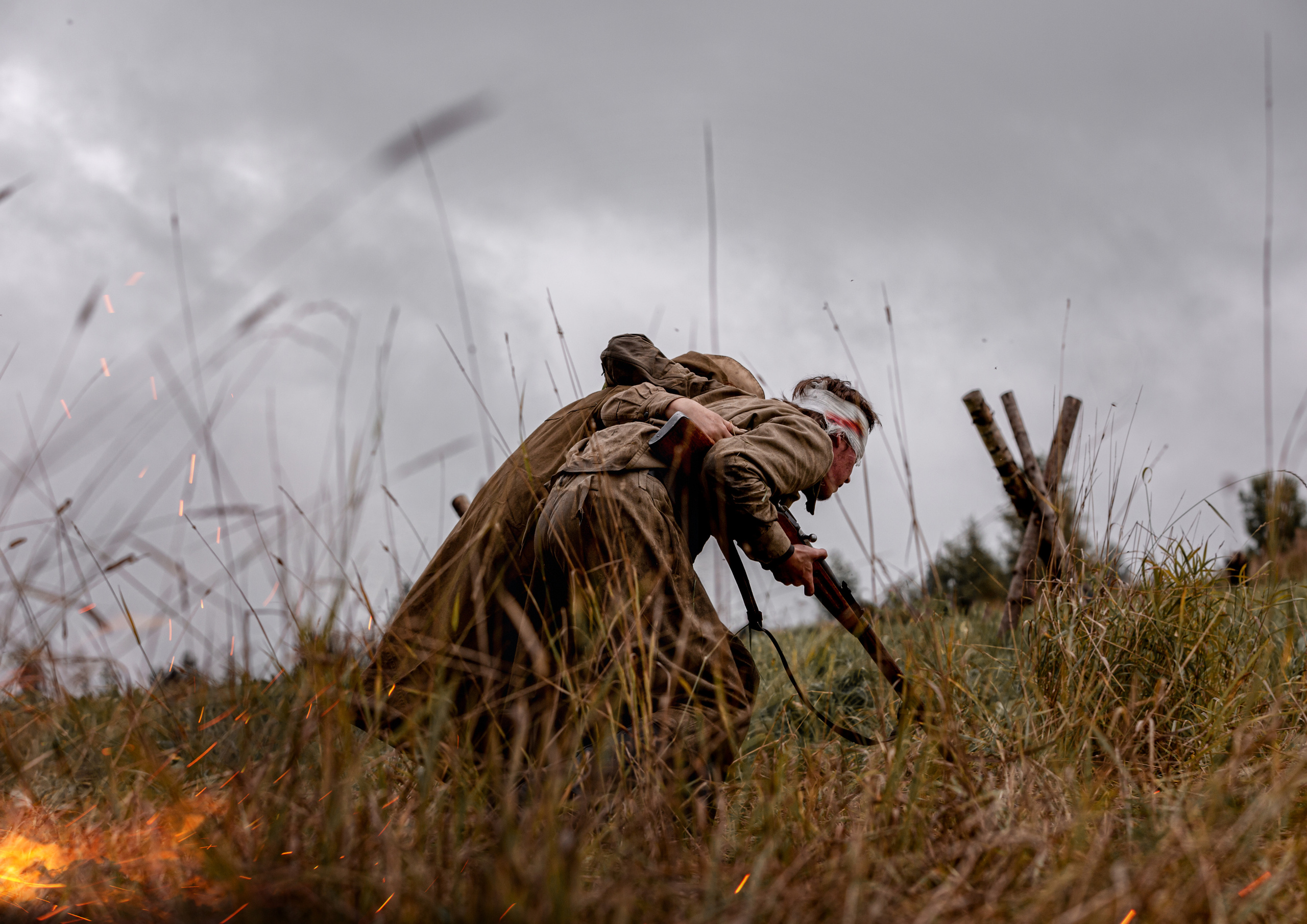 санитарка выносит раненого бойца с бинтовой повязкой на голове.