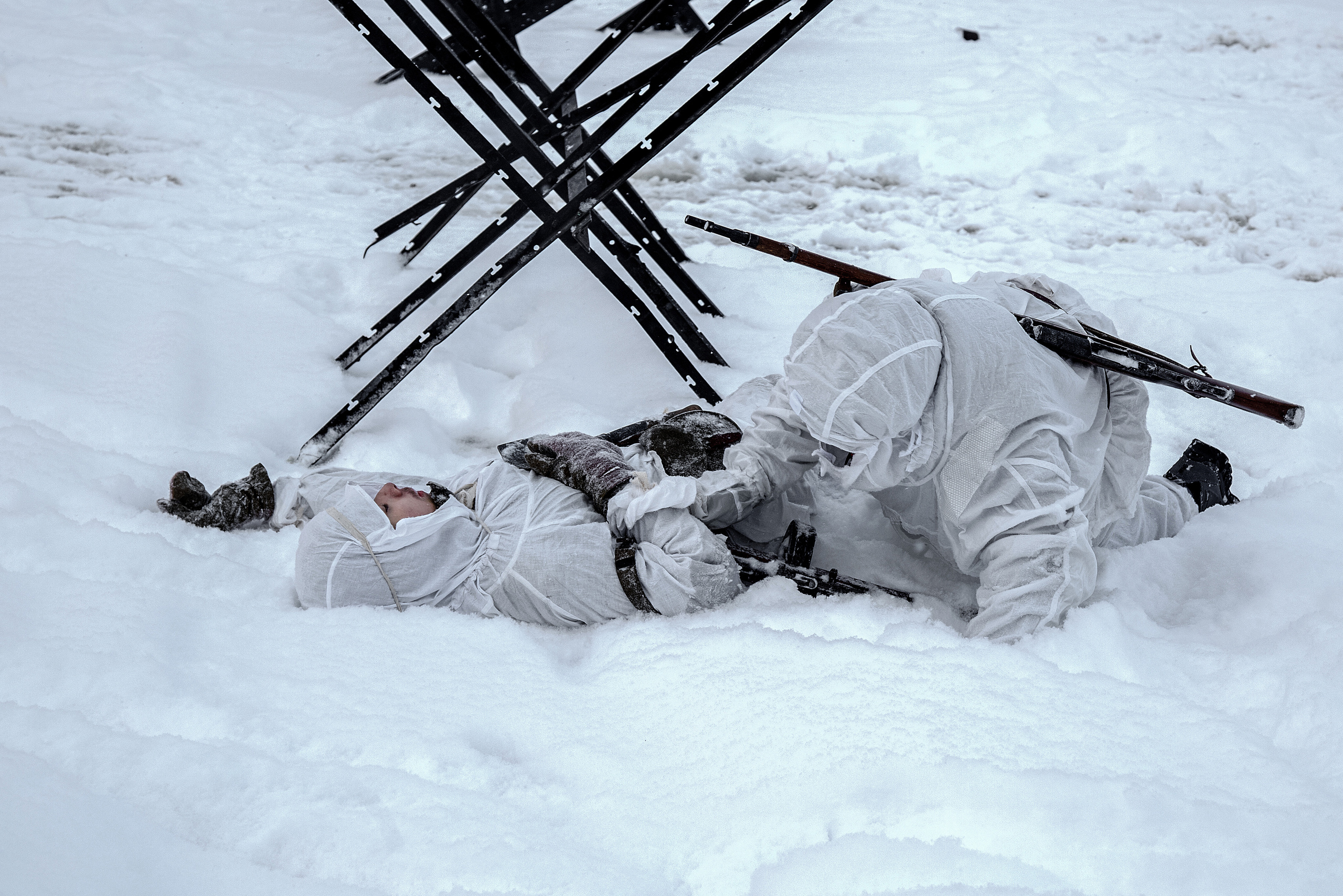 убитый разведчик в белом маскхалате. Противотанковые ежи.