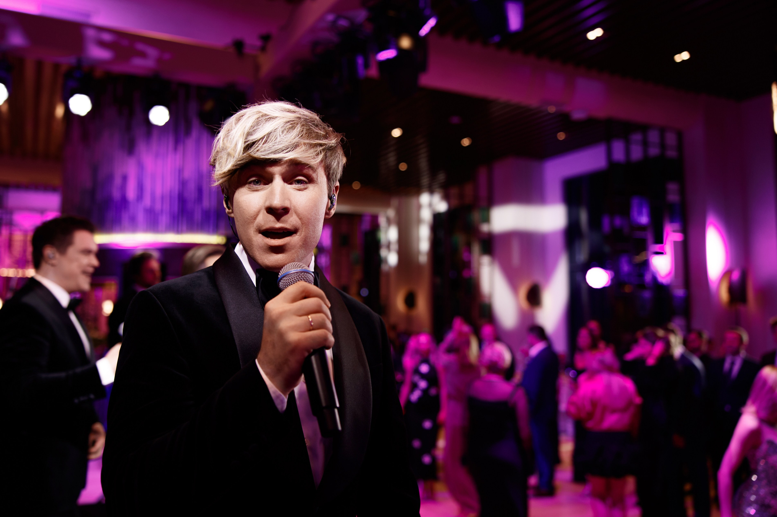 Верхнее фото: харизматичный певец из группы Кватро с микрофоном в лучах фиолетового сценического света.