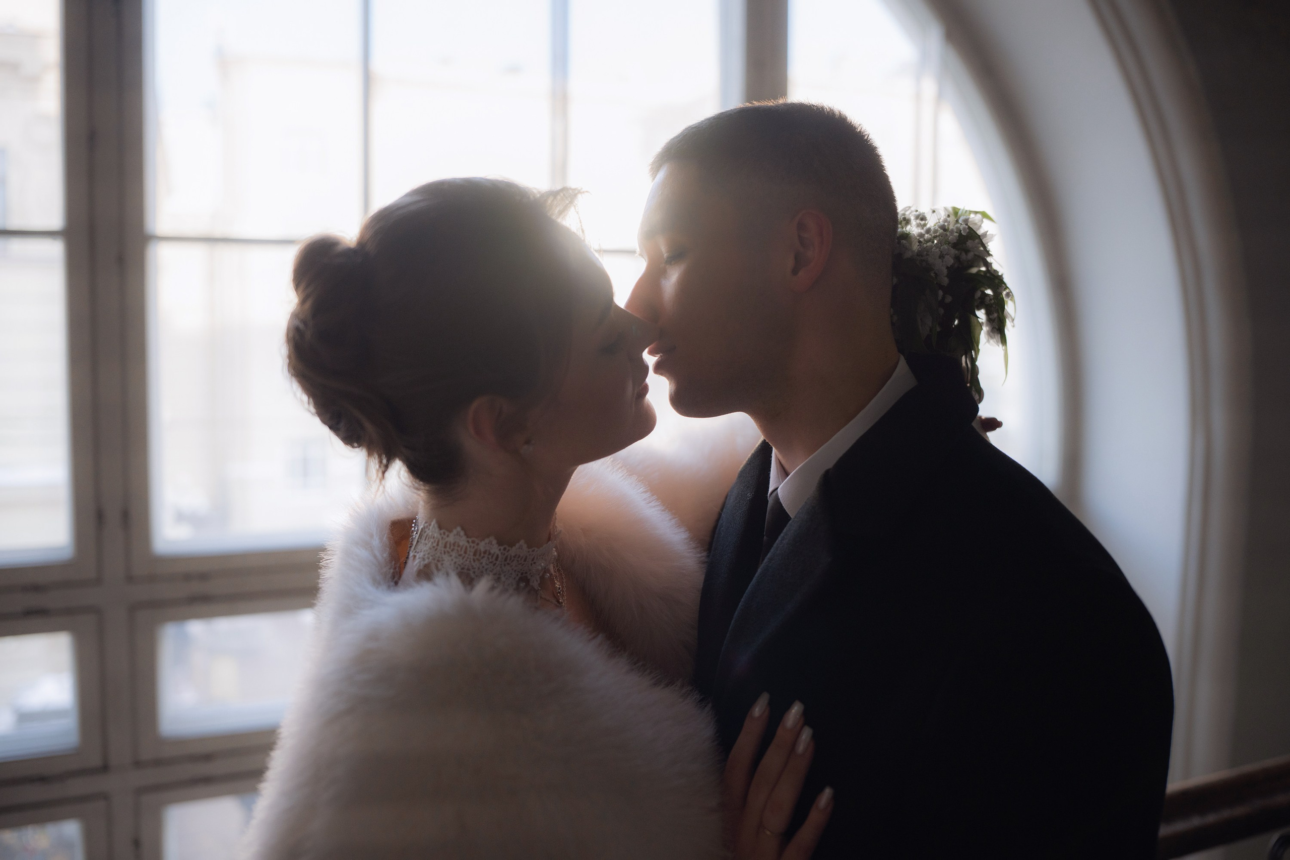 Свадебная фотосессия на Витебском вокзале в Санкт-Петербурге. Жених и невеста целуются на лестнице в контровом свете из окна
