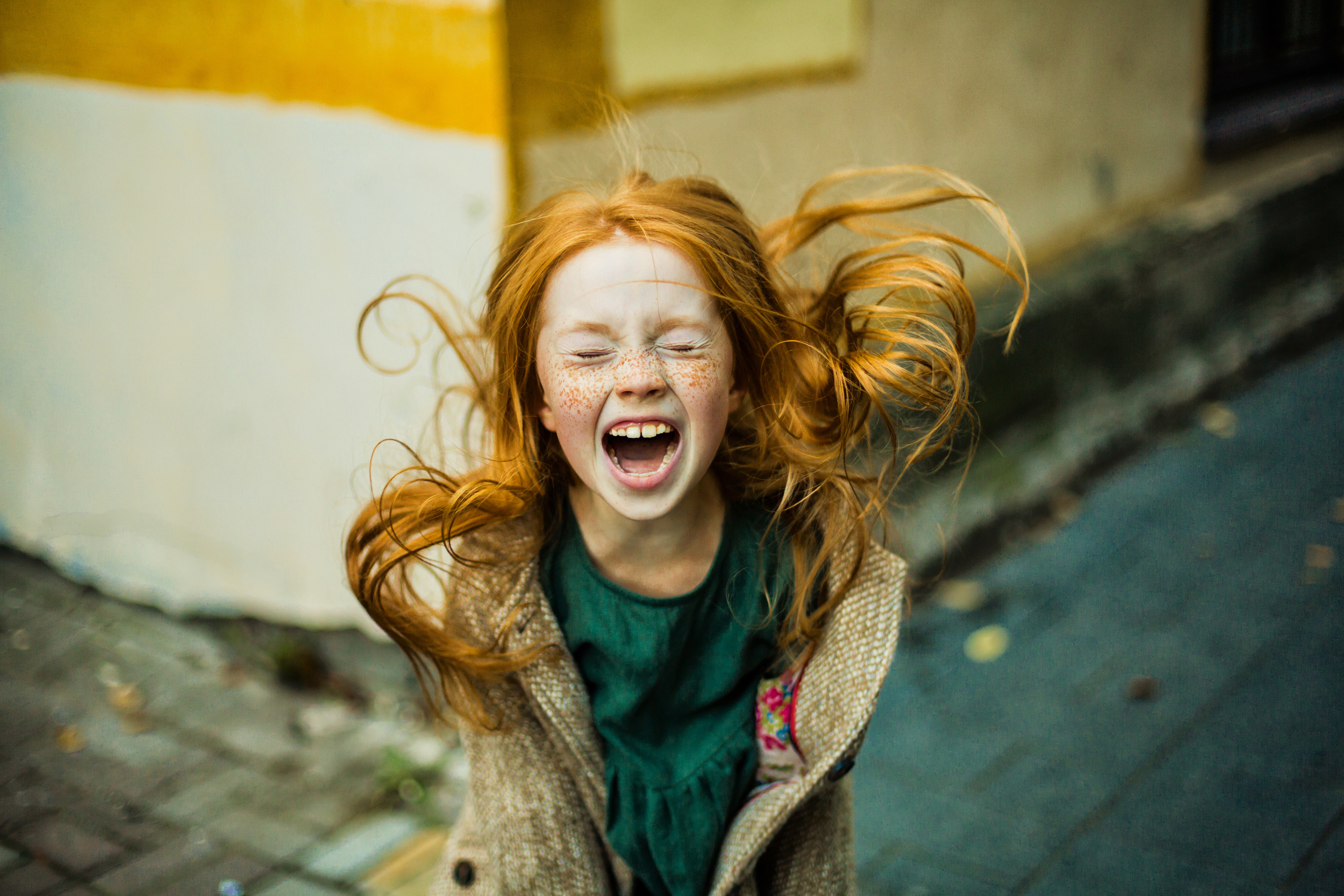 кричащая рыжая девочка с веснушками в изумрудном платье