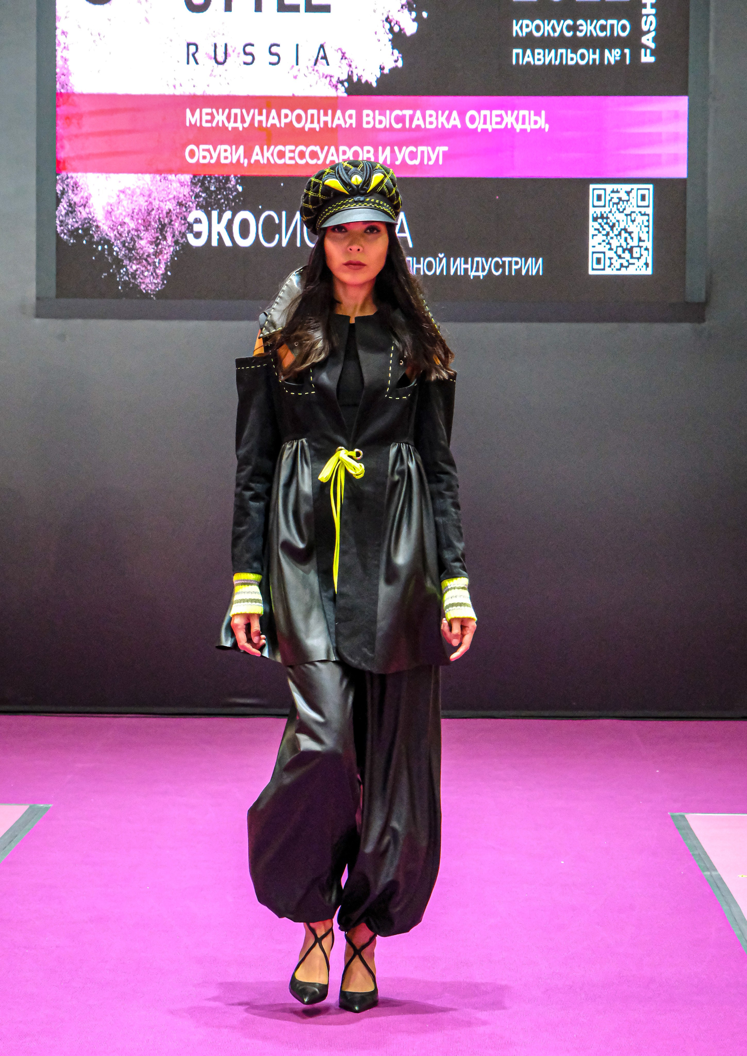  "Модели в ярких нарядах проходят по подиуму во время показа мод, освещенные яркими софитами и окруженные восторженными зрителями."