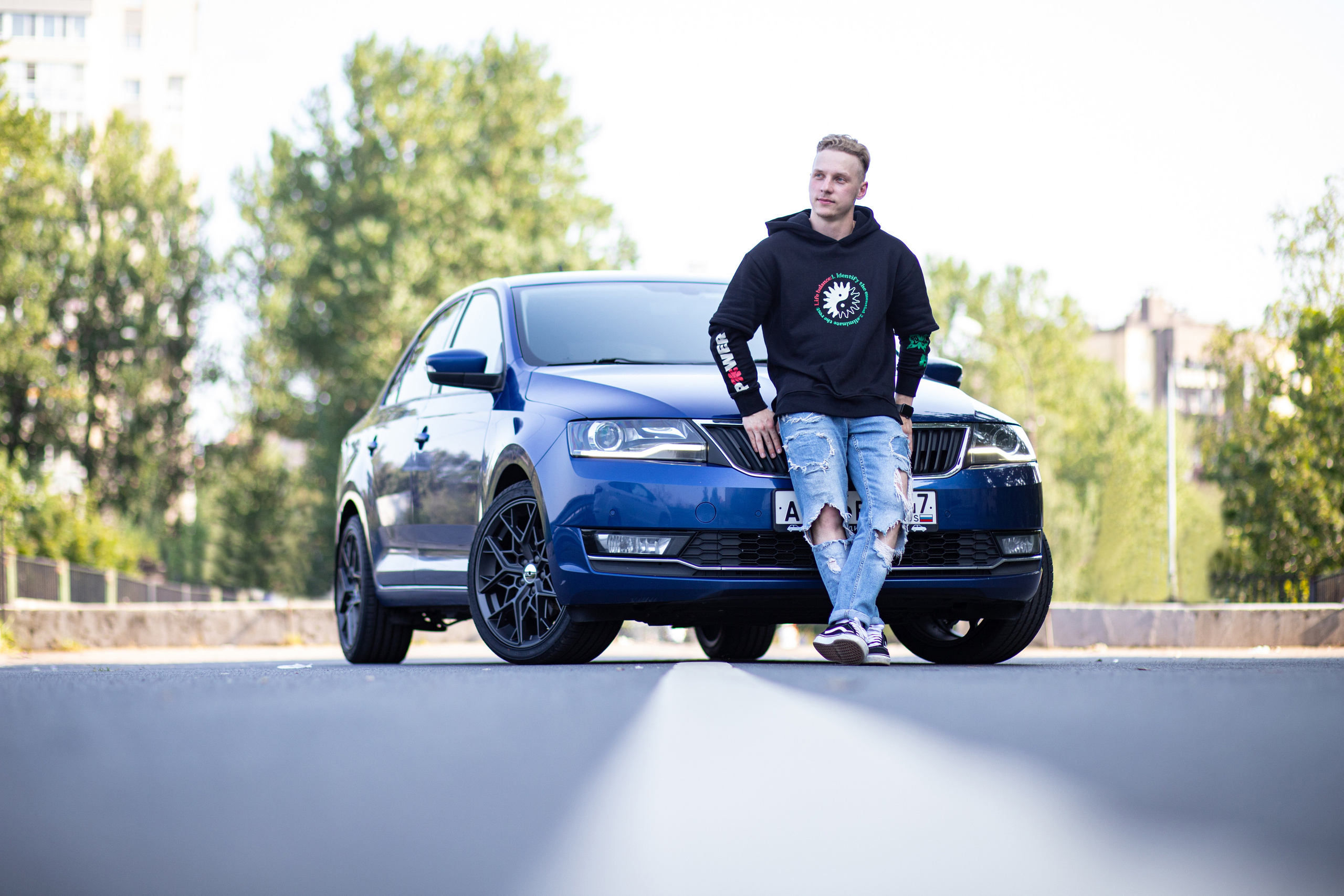 Парень на фоне синей машины летом в Санкт-Петербурге.